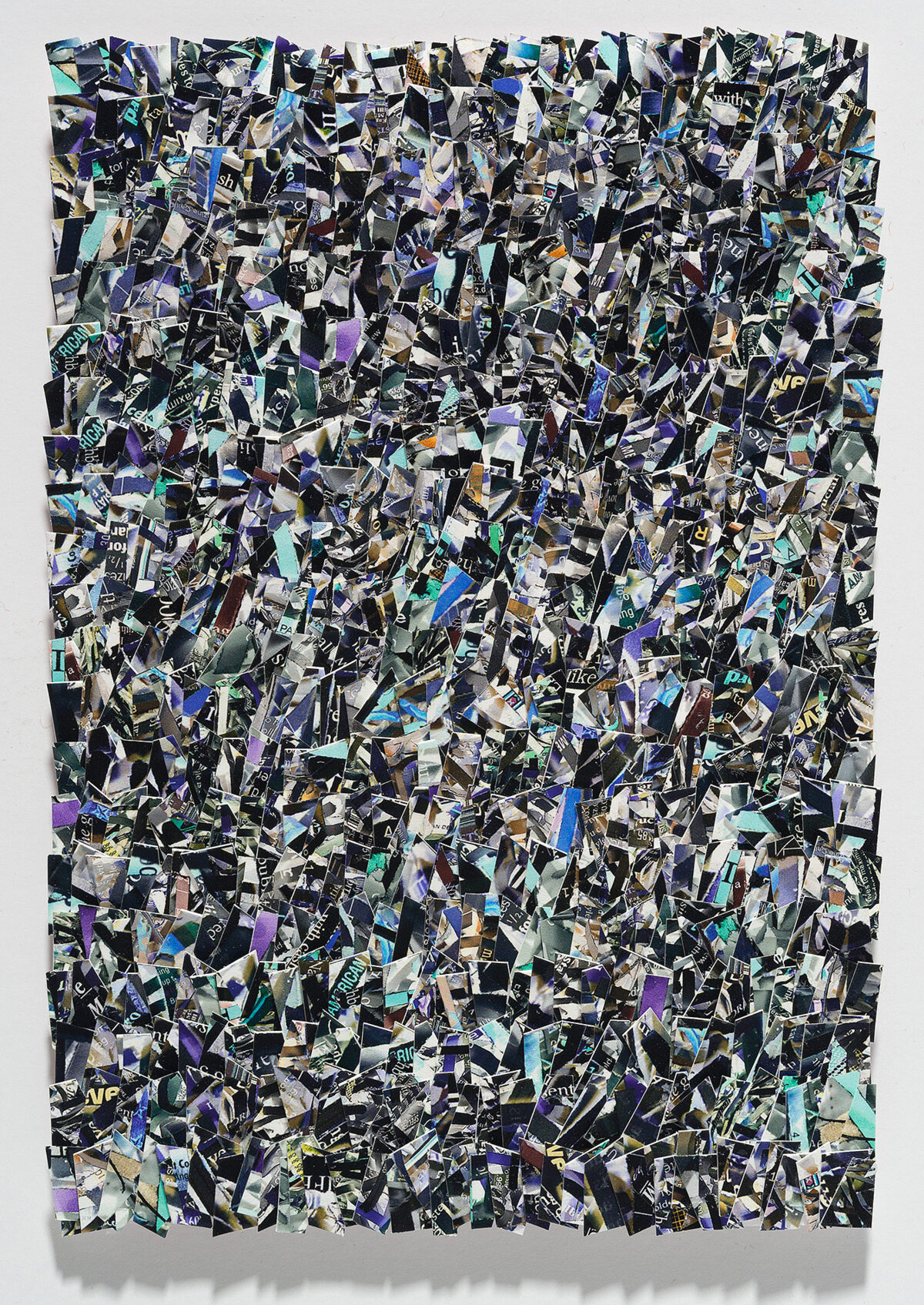 A densely layered collage of hundreds of torn and overlapping printed fragments in shades of black, white, purple, blue, cyan, and gold, creating an all-over abstract composition with no clear focal point. The irregular paper pieces are arranged in a chaotic, non-representational pattern across a rectangular format, with visible text and imagery fragments scattered throughout the surface.