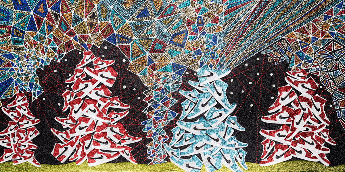 Stylized evergreen trees rendered in red, white, and turquoise arranged in stacked formation against a dark background, with an ornate geometric mosaic pattern in jewel tones filling the upper portion and a lime green ground at the base. The composition features layered cut paper elements with glittery textures and intricate linear details throughout.
