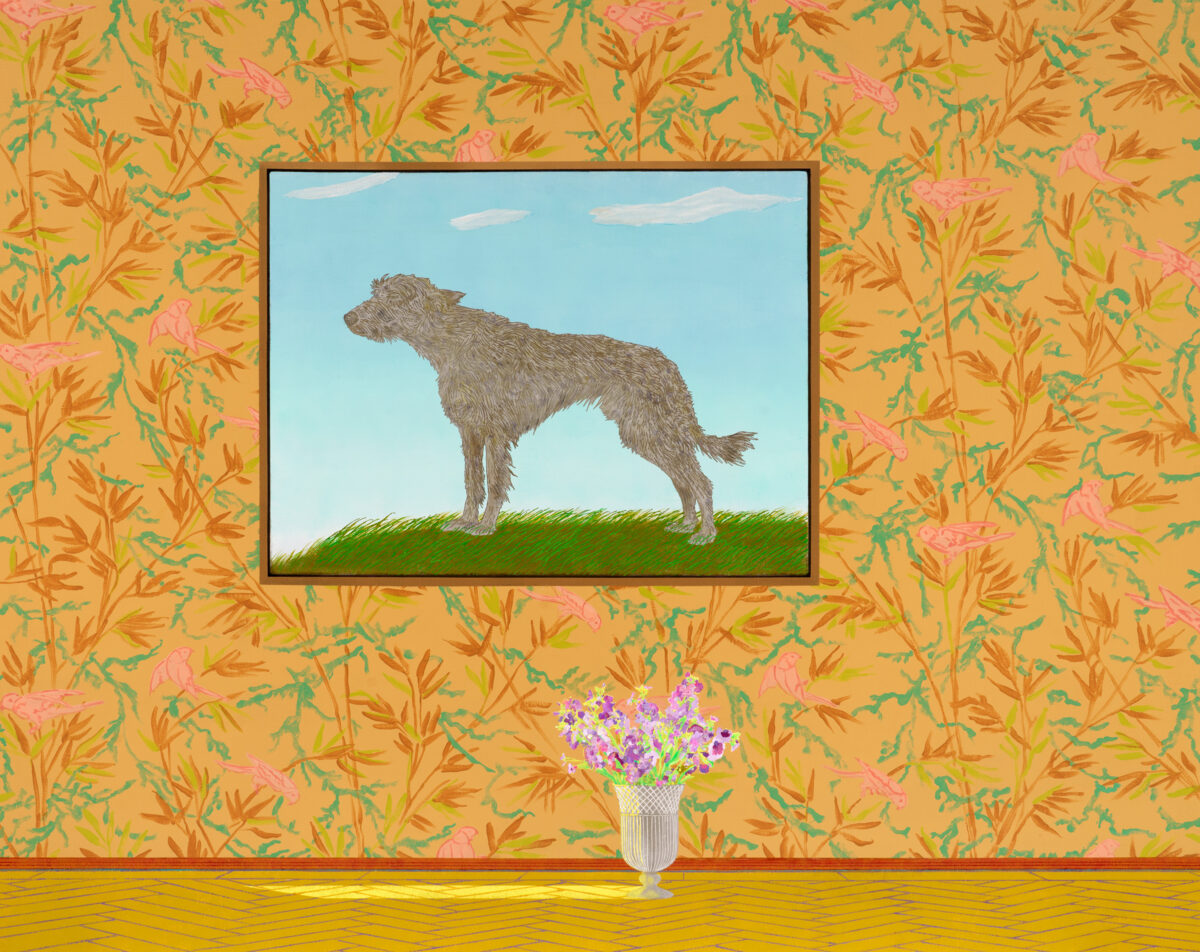 A framed portrait of a gray, shaggy dog standing on green grass against a blue sky hangs on a vibrant wallpapered wall with orange and pink botanical patterns. Below the framed work sits a classical urn containing purple flowers on a yellow wooden floor.