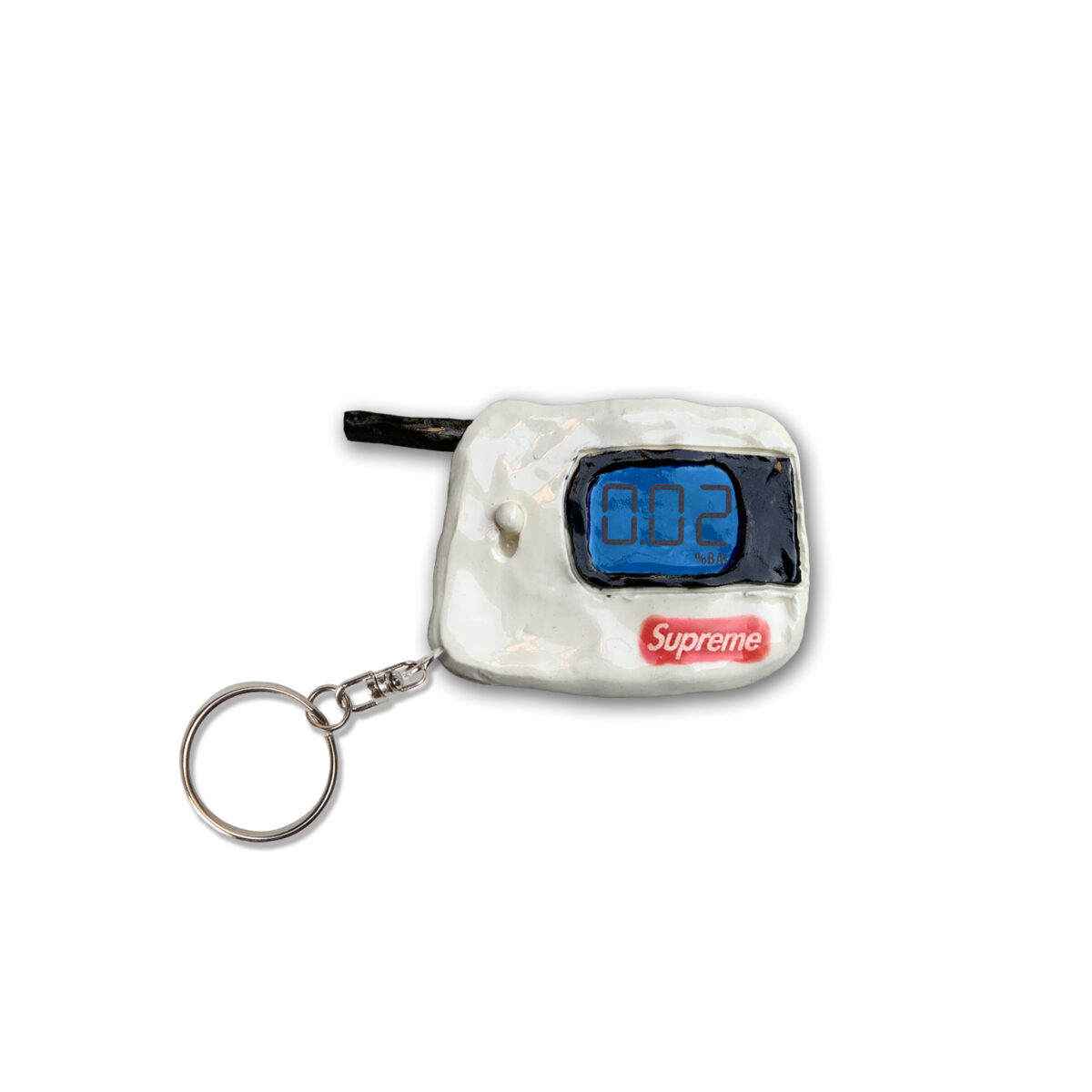 A white clay keychain featuring a blue digital display screen showing "002" and a red Supreme logo box below it, attached to a metal ring with a black cord loop extending from the top.