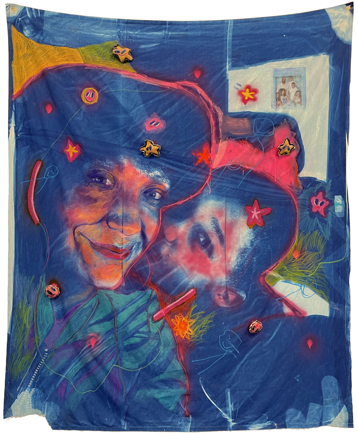 Large textile work on deep blue cotton featuring two portraits rendered in warm oranges, reds, and yellows with expressive, gestural line work. The composition includes scattered stars, flowing green botanical elements, and small photograph collage elements in the upper right, with red outlines creating dynamic movement across the surface.