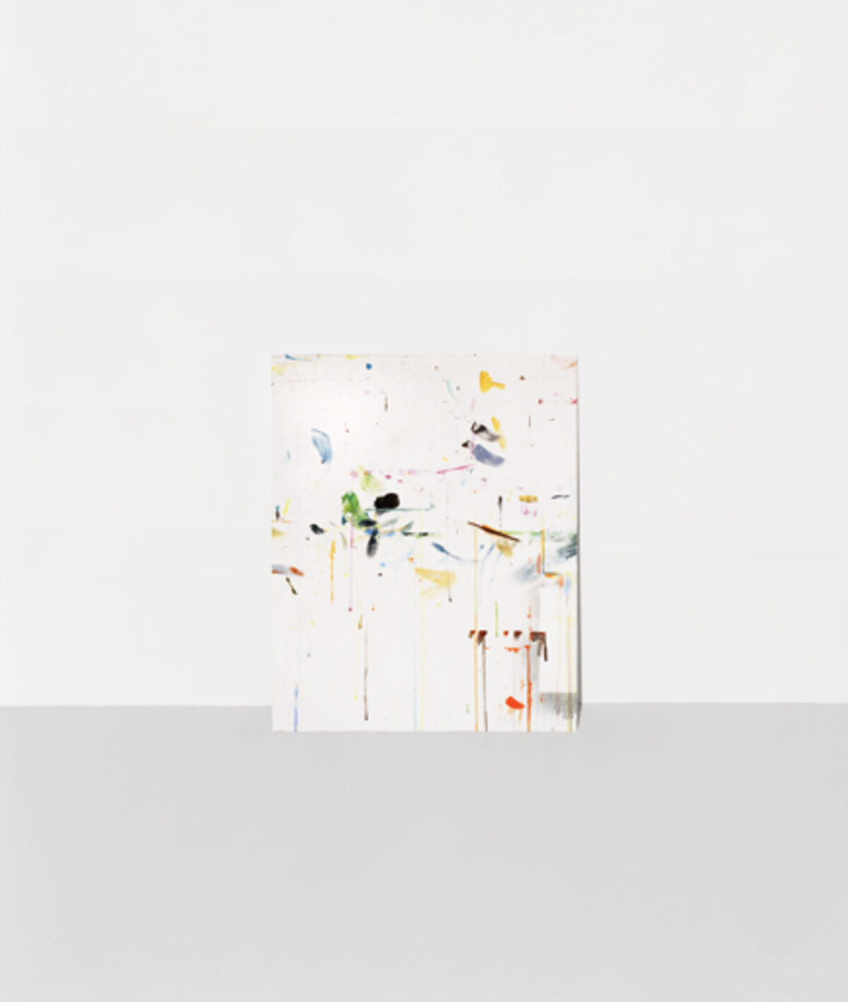 Abstract composition featuring scattered geometric shapes and organic forms in muted yellows, greens, blues, and earth tones arranged across a predominantly white background, creating a sense of dispersed movement and spatial depth.