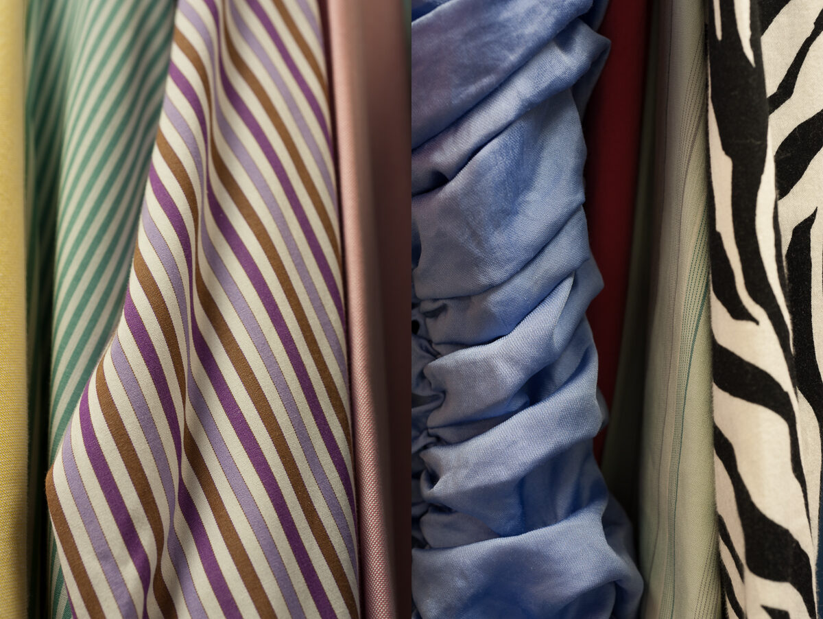 Close-up view of draped fabric samples displaying varied patterns: striped designs in purple, brown, and cream tones; solid-colored textiles in blue and burgundy; and bold zebra-stripe patterns in black and cream. The fabrics are arranged vertically with natural folds and shadows emphasizing their texture and dimensional quality.