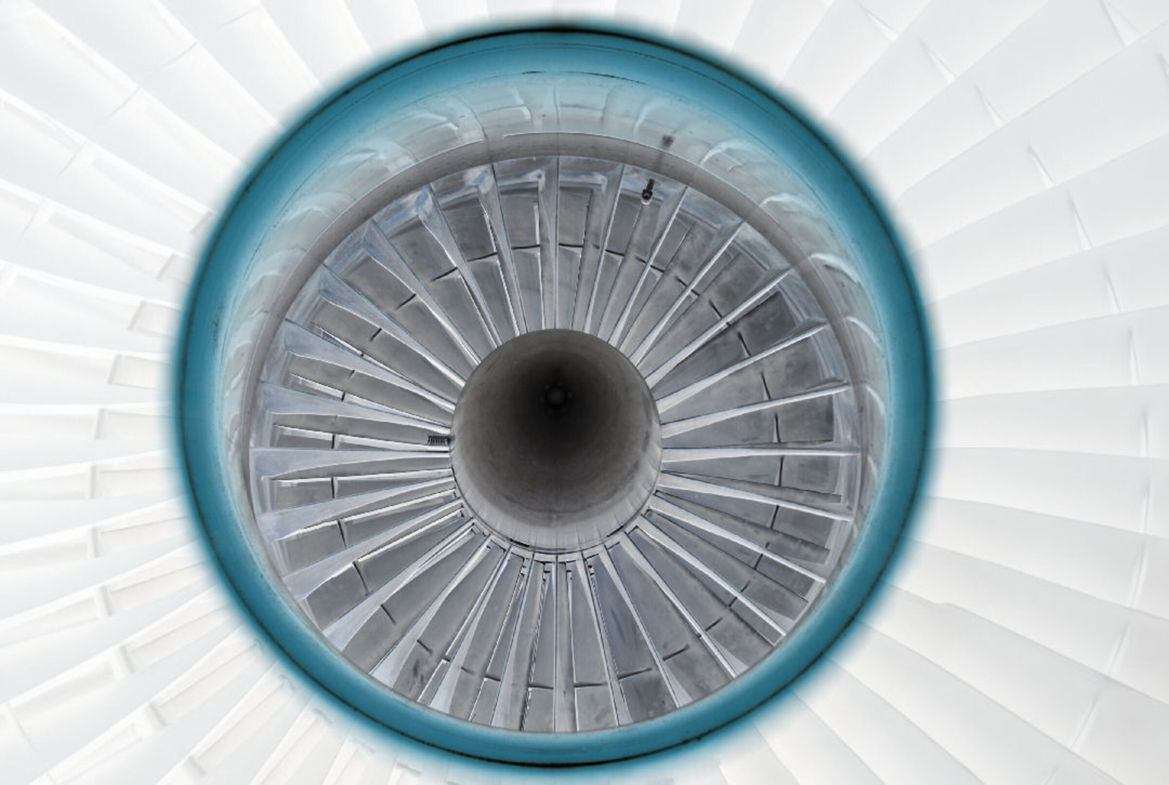 Symmetrical overhead view of a jet engine's interior, featuring concentric circles of gray turbine blades radiating from a dark central core, encased in a bright blue outer ring against a white background.