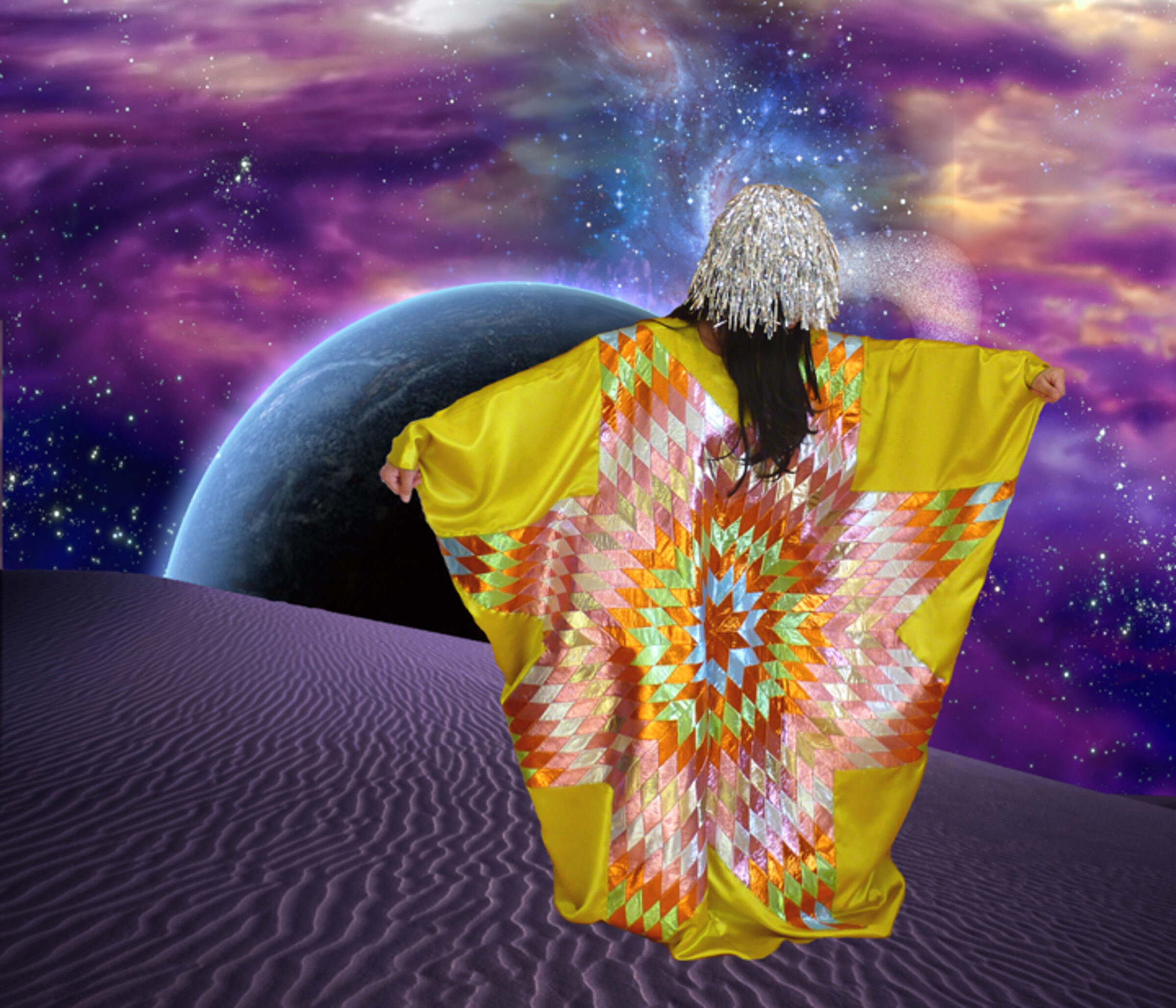 A figure with long white hair stands on a rippled desert landscape wearing a vibrant yellow garment with geometric patterns in orange, red, and white. Behind them, a glowing planet hovers against a cosmic sky of purple, blue, and golden clouds scattered with stars.