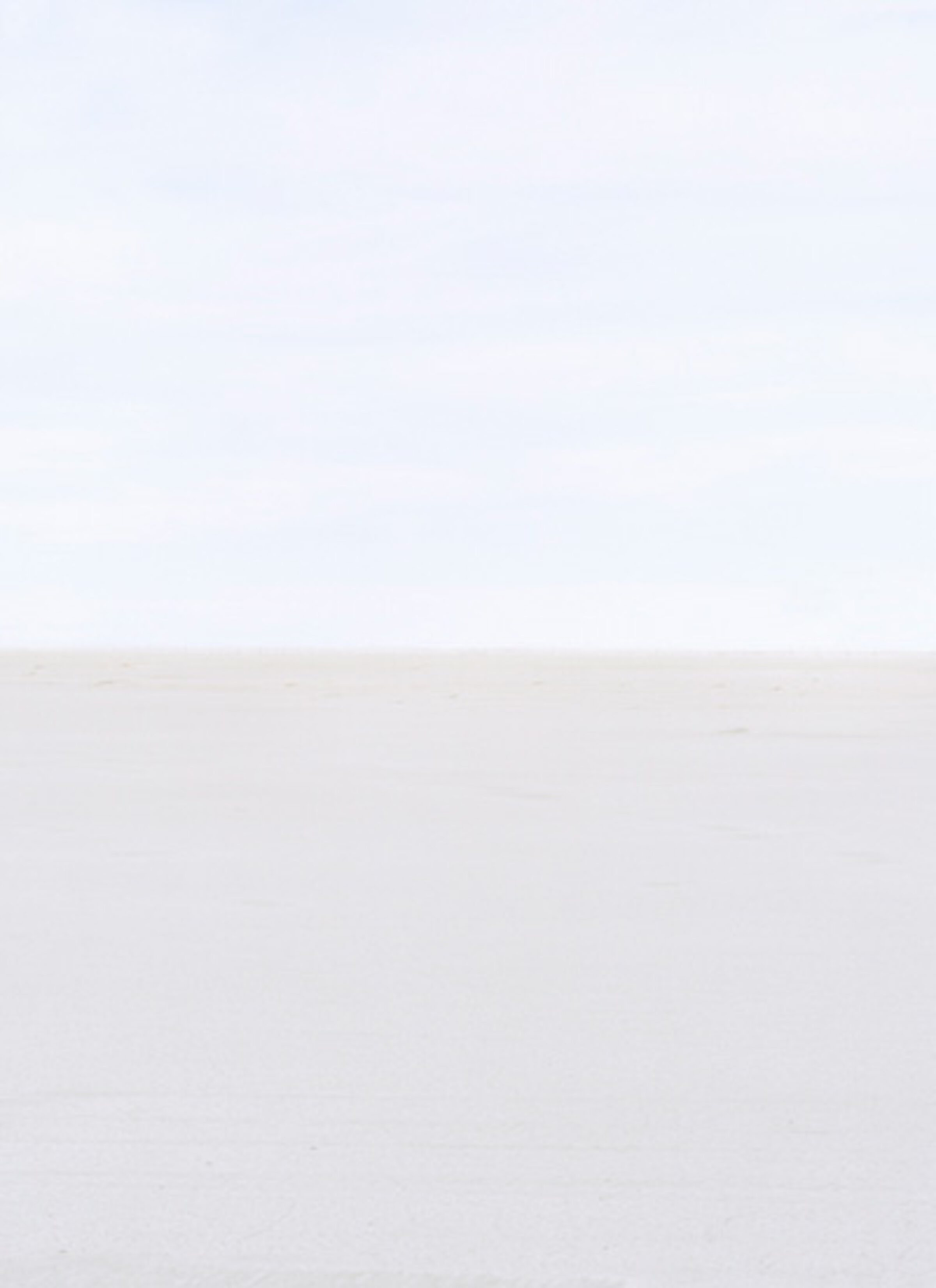 Minimalist composition divided horizontally into two tonal zones—a pale blue-gray upper section meeting a lighter beige-white lower section at a subtle horizon line. The soft, monochromatic palette and gentle gradations create a serene, atmospheric landscape.