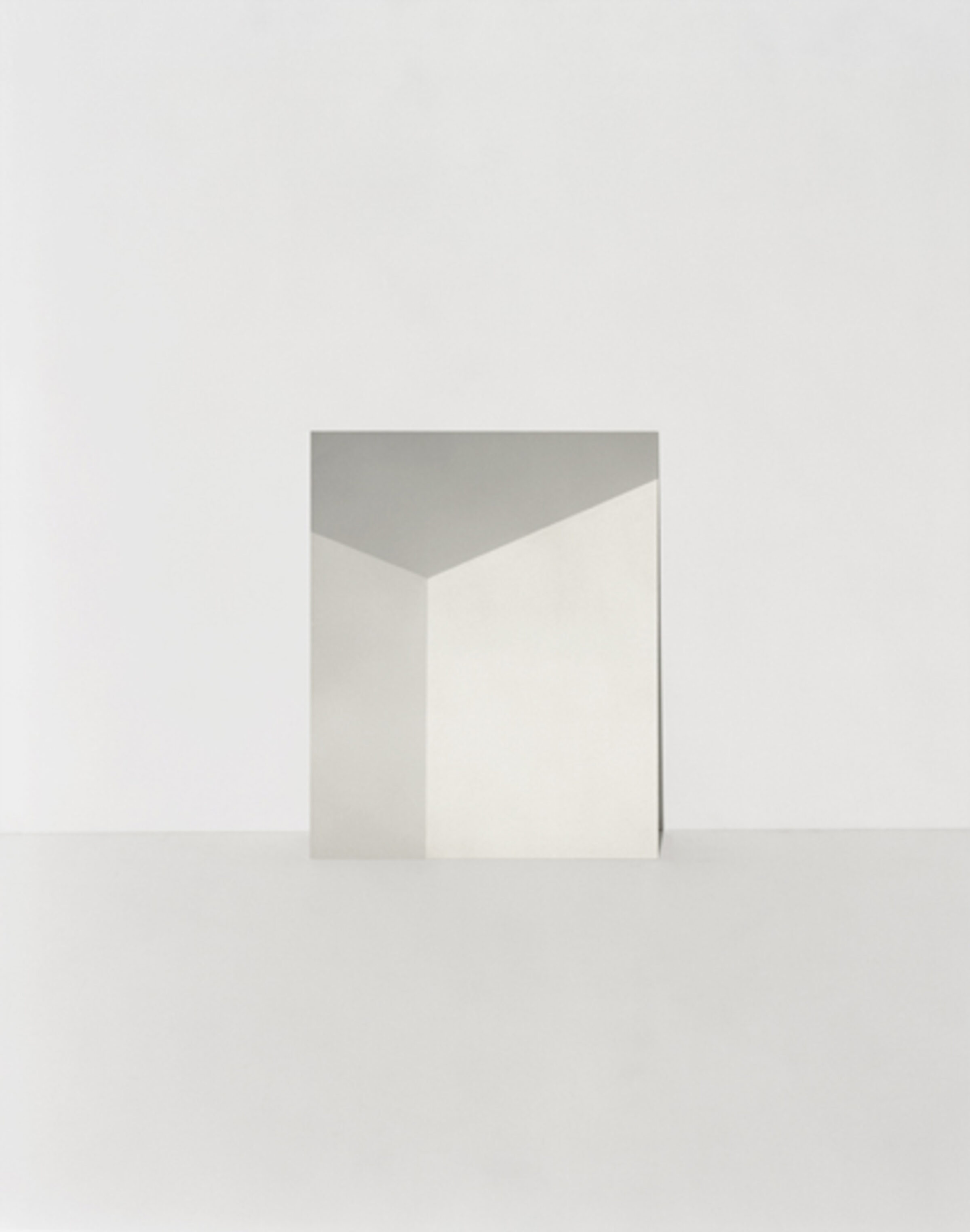 Minimalist composition featuring an open white envelope or folded paper form against a soft beige background, with a gray geometric plane visible at the top edge, creating a subtle study in negative space and neutral tones.