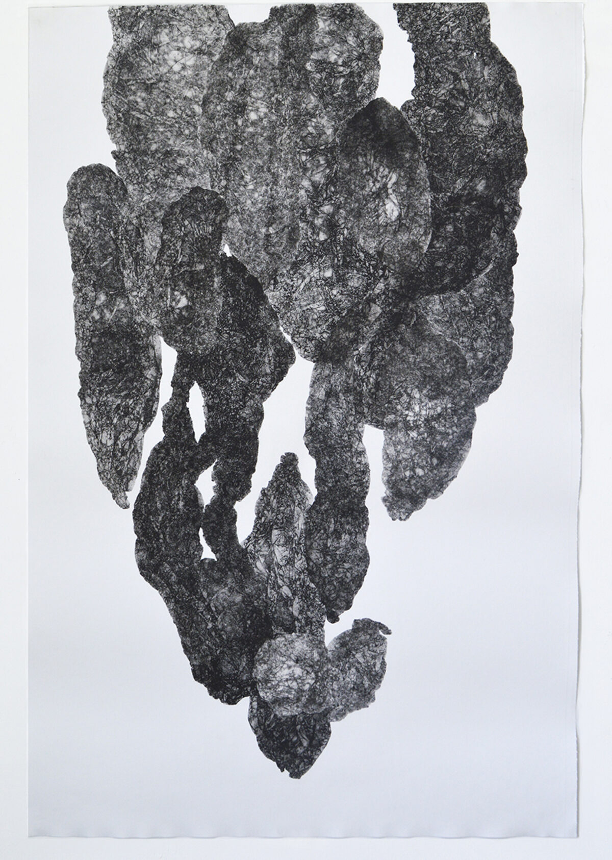 A textured, dark gray monoprint on white paper depicting an abstract, vertical form composed of layered, organic shapes with rough, granular surfaces. The composition suggests fragmented or stacked geological formations, with lighter areas creating depth and contrast throughout the composition.