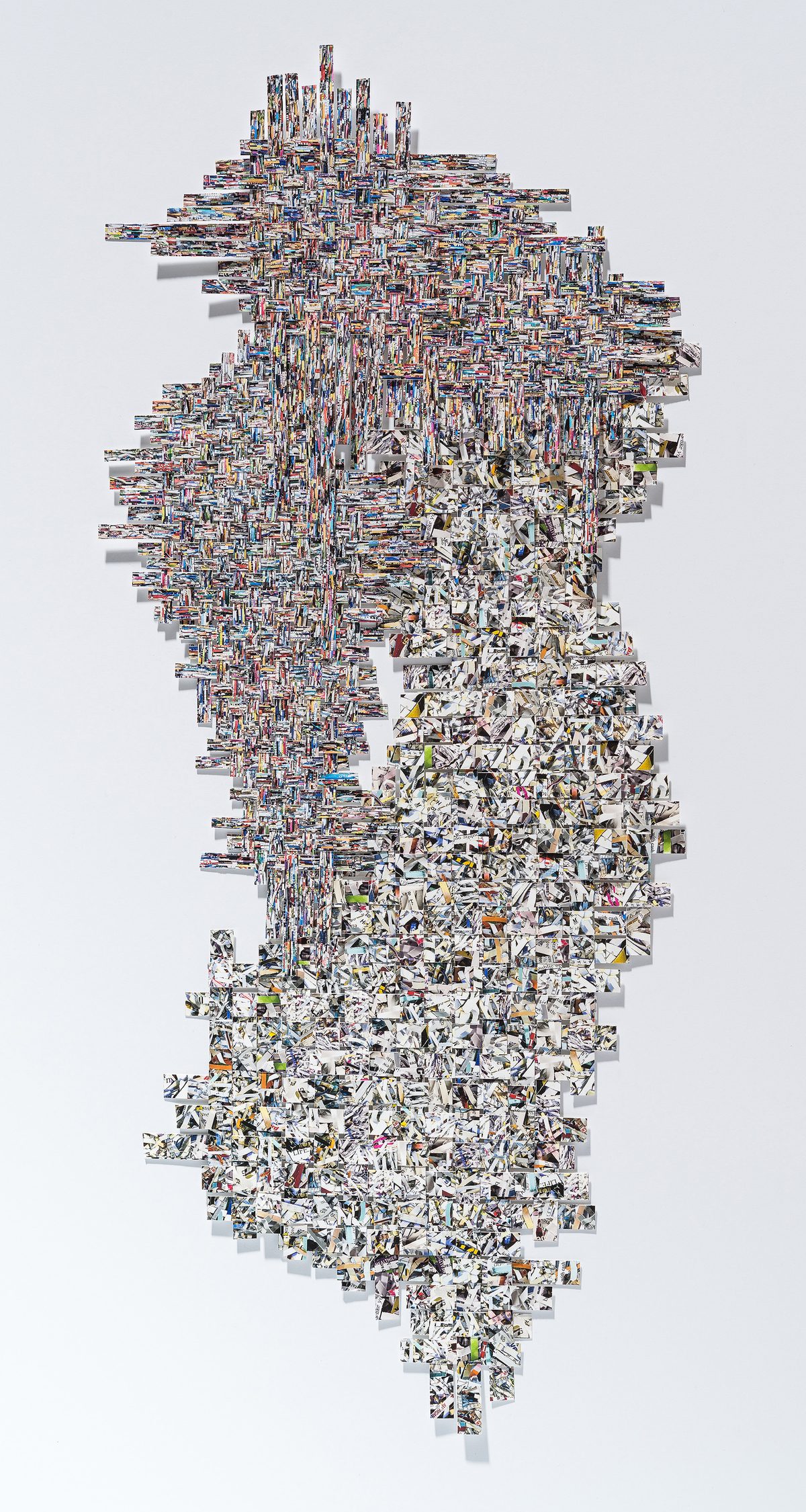 A vertical collage composed of hundreds of small photographic fragments arranged in a dense, organic pattern. The upper portion features tightly layered colorful images creating an intricate woven texture, while the lower half transitions to predominantly white and grayscale fragments that taper toward the bottom, creating a cascading effect against a white background.