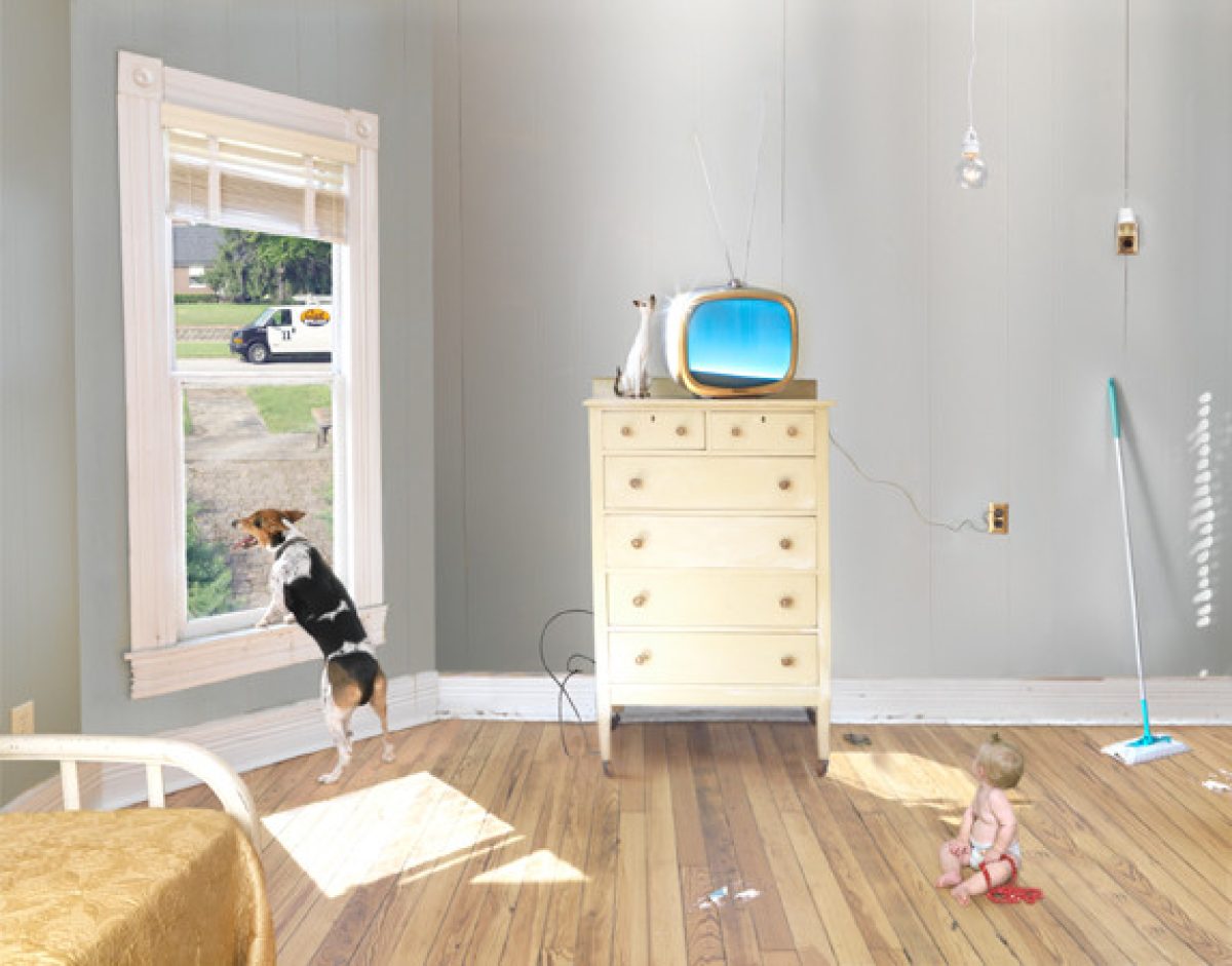 A bright, sunlit domestic interior with warm wood flooring features a yellow dresser topped with a vintage television displaying a blue sky image, alongside white ceramic vessels and hanging pendant lights. In the foreground, a dog peers through an open door toward the exterior, while a child in pink sits on the floor near cleaning supplies, and another figure rests on a bed in the lower left, creating a layered scene of everyday domestic life.