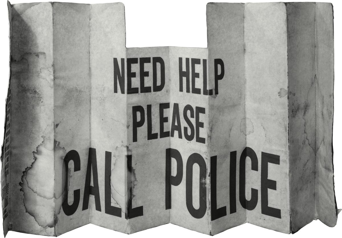 A weathered, accordion-folded metal panel resembling a car windshield sun shade, printed with bold black text reading "NEED HELP PLEASE CALL POLICE." The surface shows creasing, discoloration, and wear consistent with prolonged outdoor use.