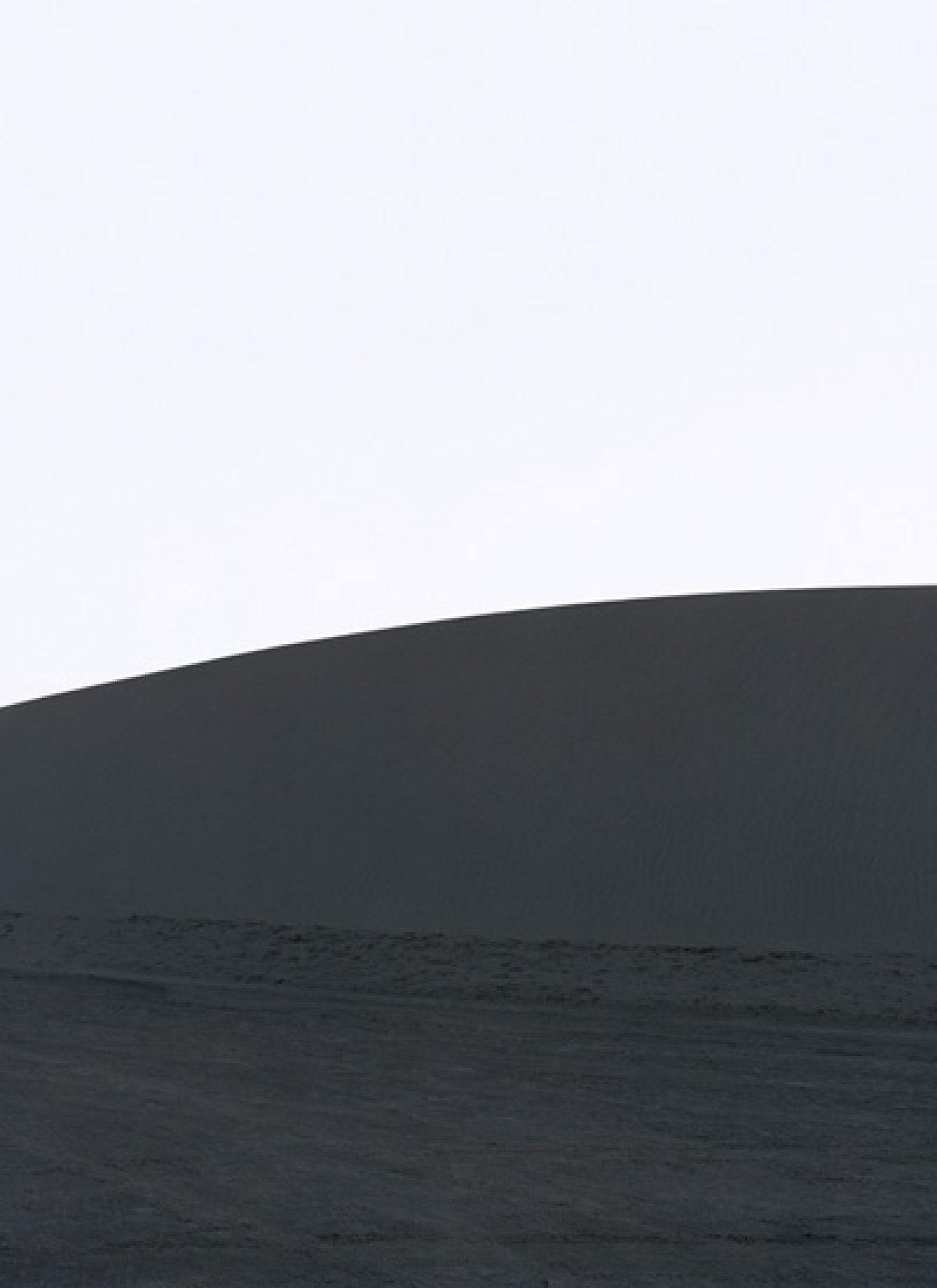 Minimalist composition dividing the frame horizontally into a pale upper section and dark lower half, with a curved horizon line suggesting an abstract landscape or geological formation. Subtle tonal gradations and soft focus create a contemplative, atmospheric quality.