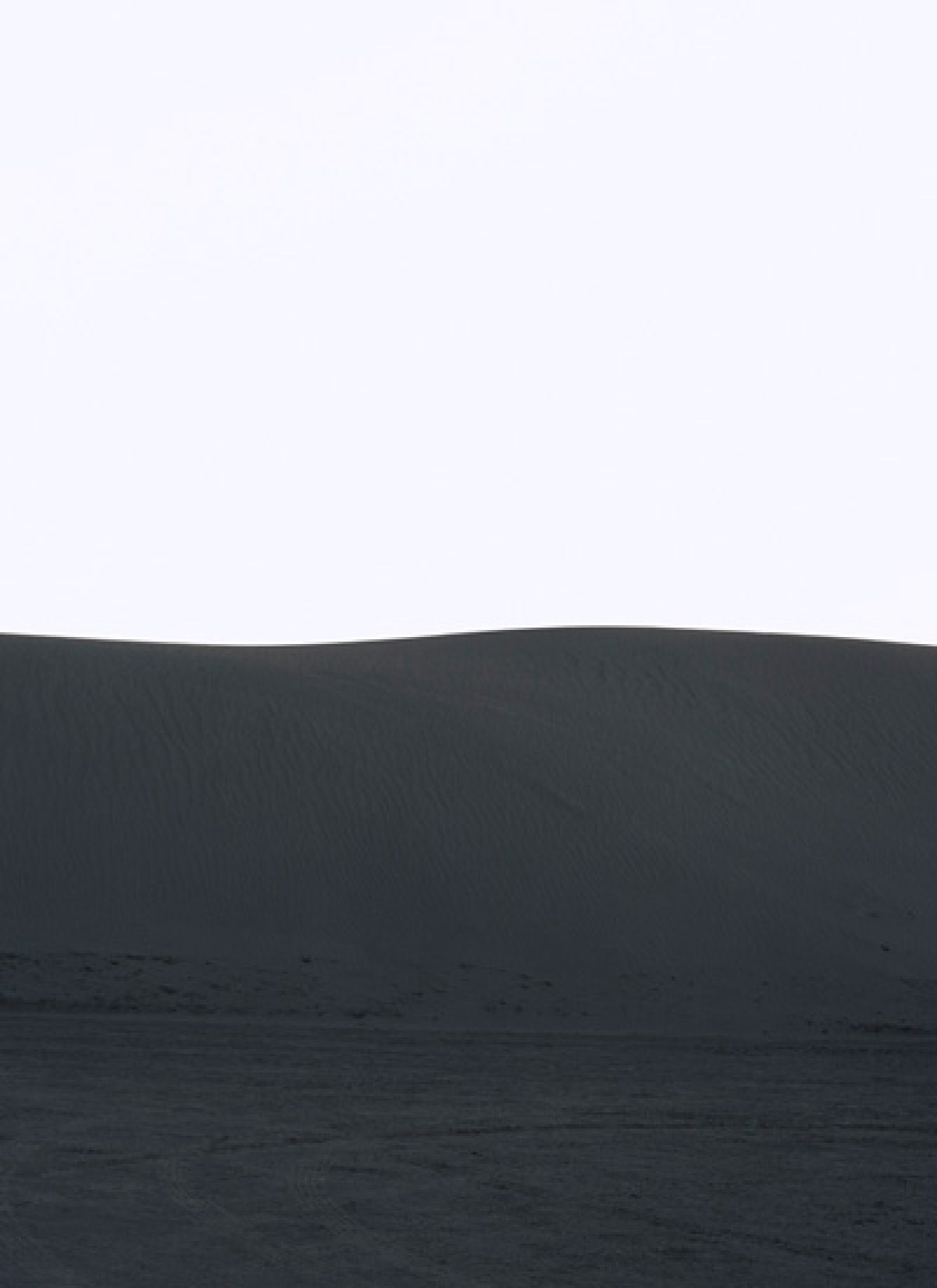Minimalist landscape with a pale gray sky above a dark charcoal horizon line, beneath which lies a textured darker plane suggesting water or terrain, creating a stark division of tones and planes across the composition.