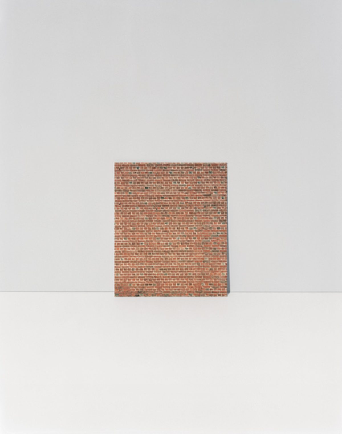 A rectangular brick wall section rendered in terracotta and rust tones occupies the center of a minimalist composition, positioned against a soft gray background divided by a horizontal white plane.