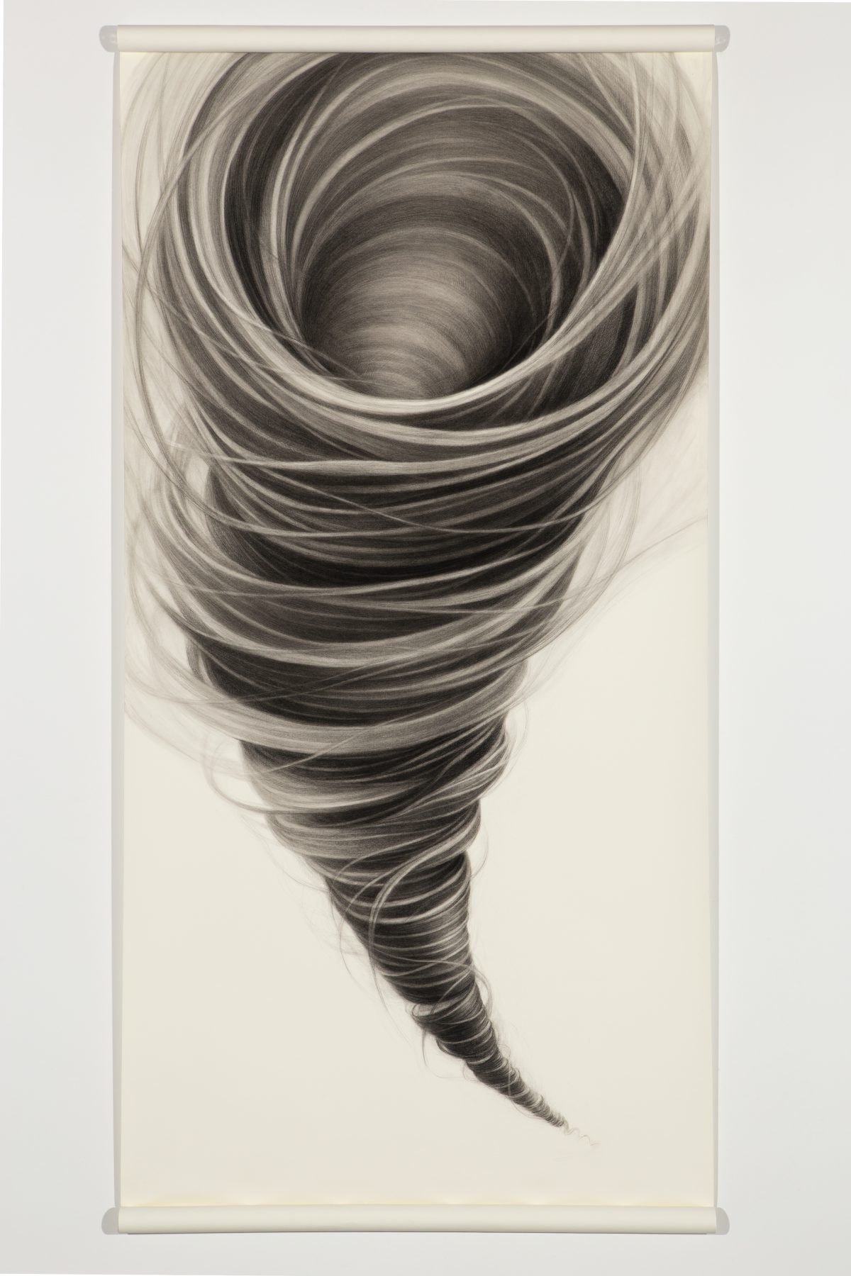 A dramatic spiral composition rendered in charcoal depicts a tornado viewed from above, with concentric swirling lines that gradually darken toward the center void. The tightly wound bands of gray and black create a hypnotic sense of motion and depth against the pale paper ground.