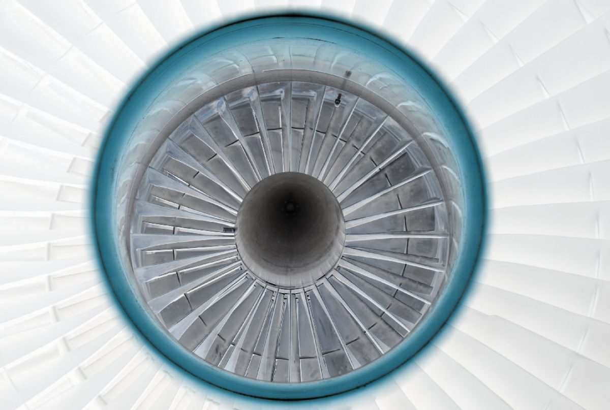 Symmetrical overhead view of a jet engine's interior, featuring concentric circles of gray turbine blades radiating from a dark central core, encased in a bright blue outer ring against a white background.
