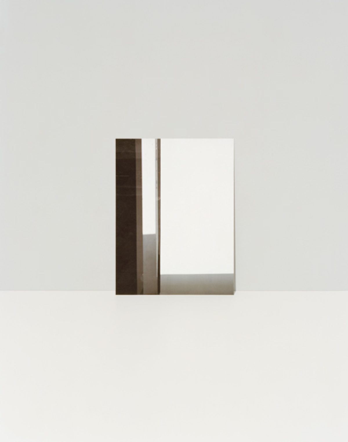 Minimalist composition featuring geometric forms in neutral tones—a dark brown vertical rectangle, light gray horizontal elements, and a white rectangular panel arranged against a pale beige background, creating subtle spatial depth through overlapping planes.
