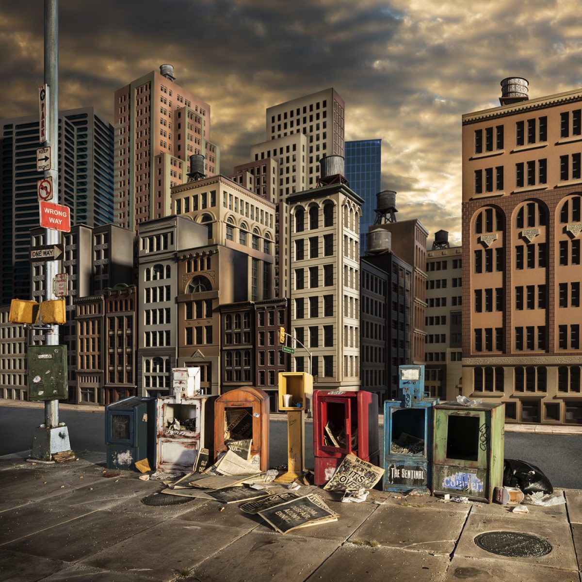 A dystopian urban streetscape dominated by towering brick and stone buildings with water towers on their roofs, beneath a dramatic clouded sky. In the foreground, a row of abandoned, deteriorating newspaper boxes and street furniture in various colors—red, yellow, blue, and green—sit discarded on a concrete sidewalk beside a utility pole with traffic signs, creating a stark contrast between the monumental architecture and the detritus of urban decay.