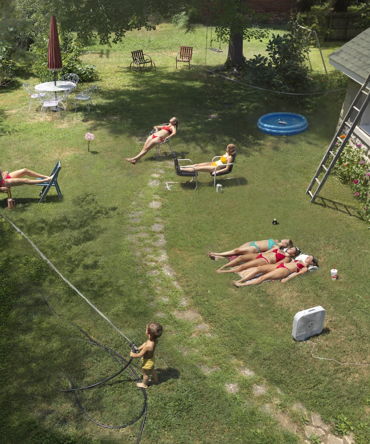 Aerial view of a backyard scene with multiple people in various states of relaxation and leisure activity scattered across a lawn. Figures recline on lounge chairs and grass, one person operates a trampoline, and a child holds a jump rope, while garden furniture, a blue inflatable pool, and trees frame the composition.