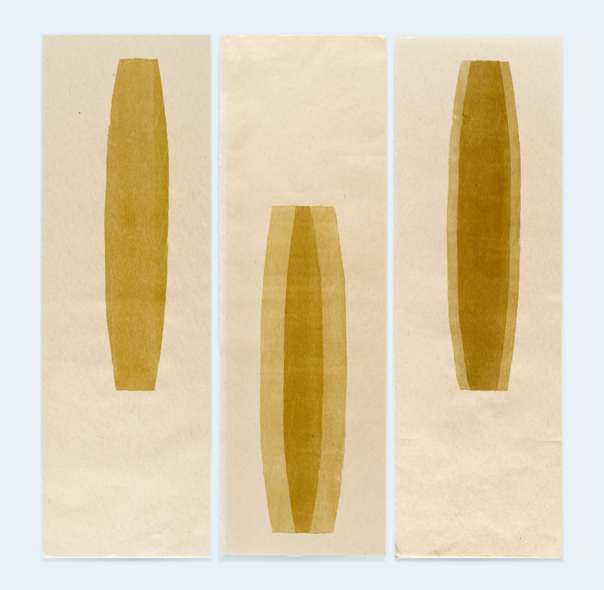 Three vertical panels featuring golden-brown elongated oval shapes on cream-colored paper. The left and right panels display similar narrow forms with subtle shading, while the center panel shows a wider, more tapered oval with deeper tonal variations creating dimensional depth.