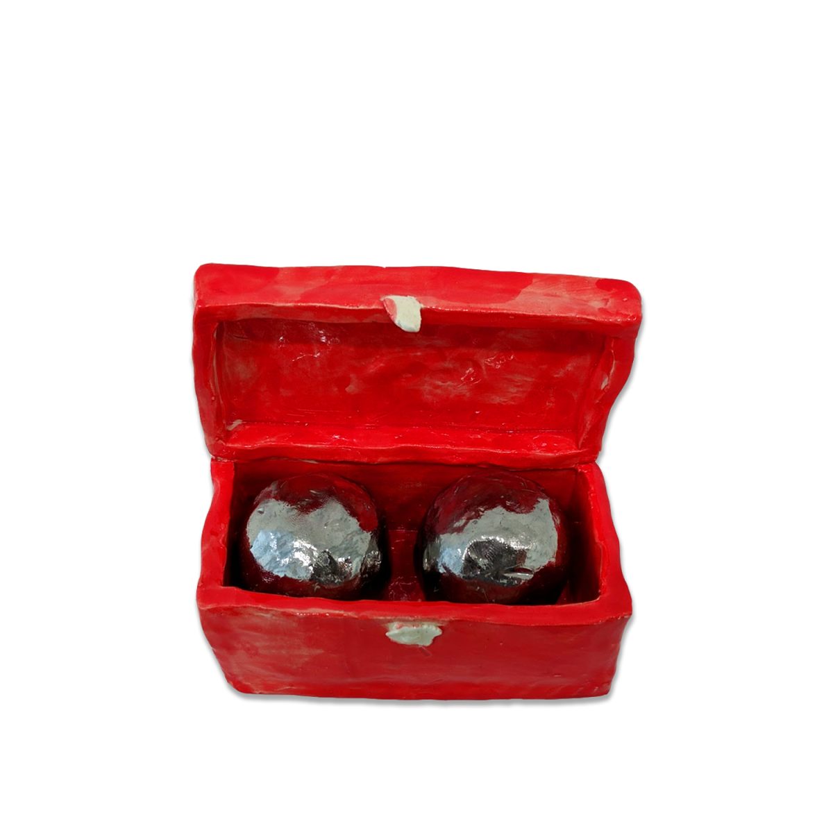 A bright red clay box with hinged lid sits open to reveal two dark spherical objects with silvery metallic surfaces nestled inside.