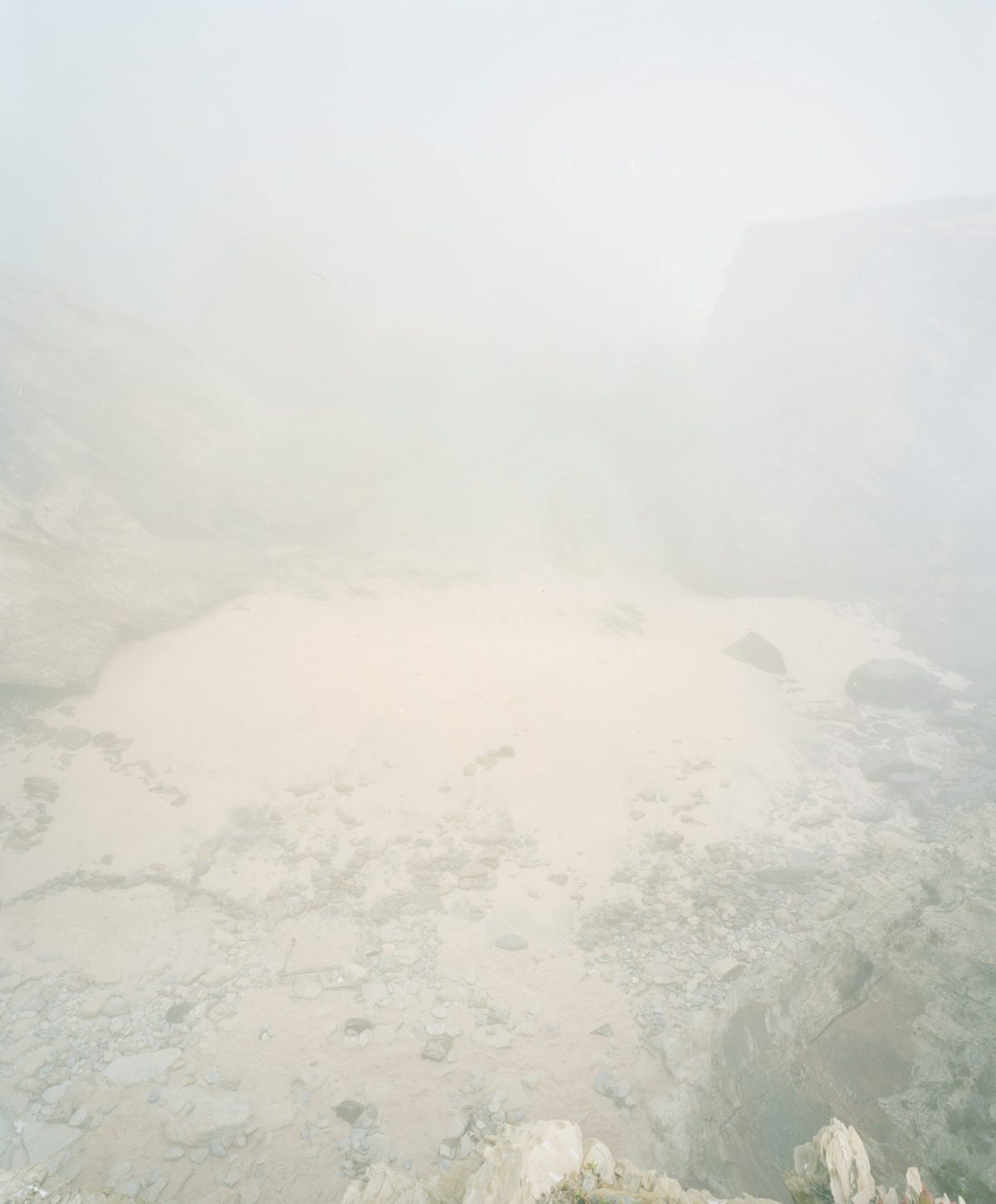 Hazy aerial view of a geothermal landscape with steaming vents and mineral-deposited terrain, rendered in soft whites and grays with minimal visibility through dense vapor and mist.