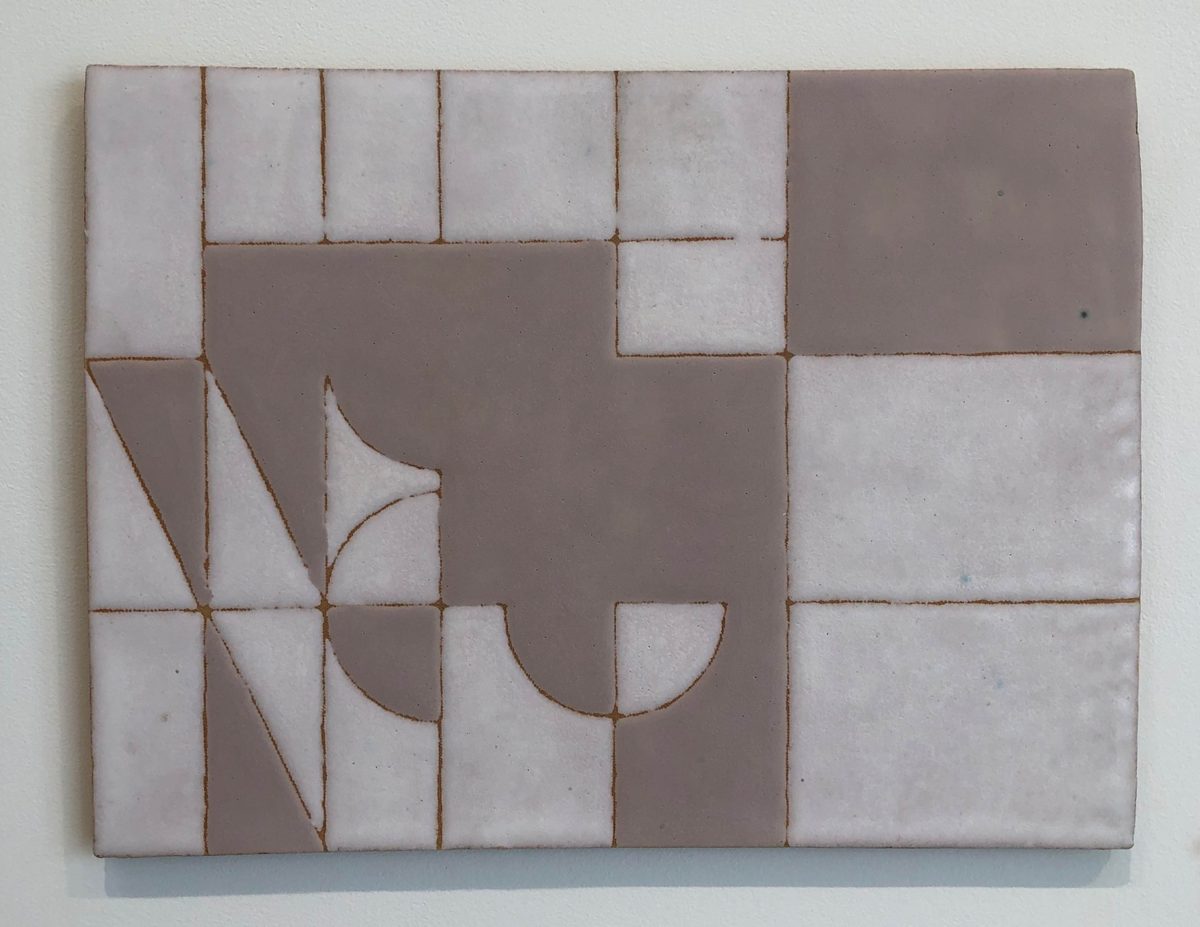 A ceramic tile panel featuring a grid of cream and brown tiles arranged in an irregular pattern. Curved linear incisions create geometric and organic shapes across the surface, forming abstract designs that span multiple tiles.