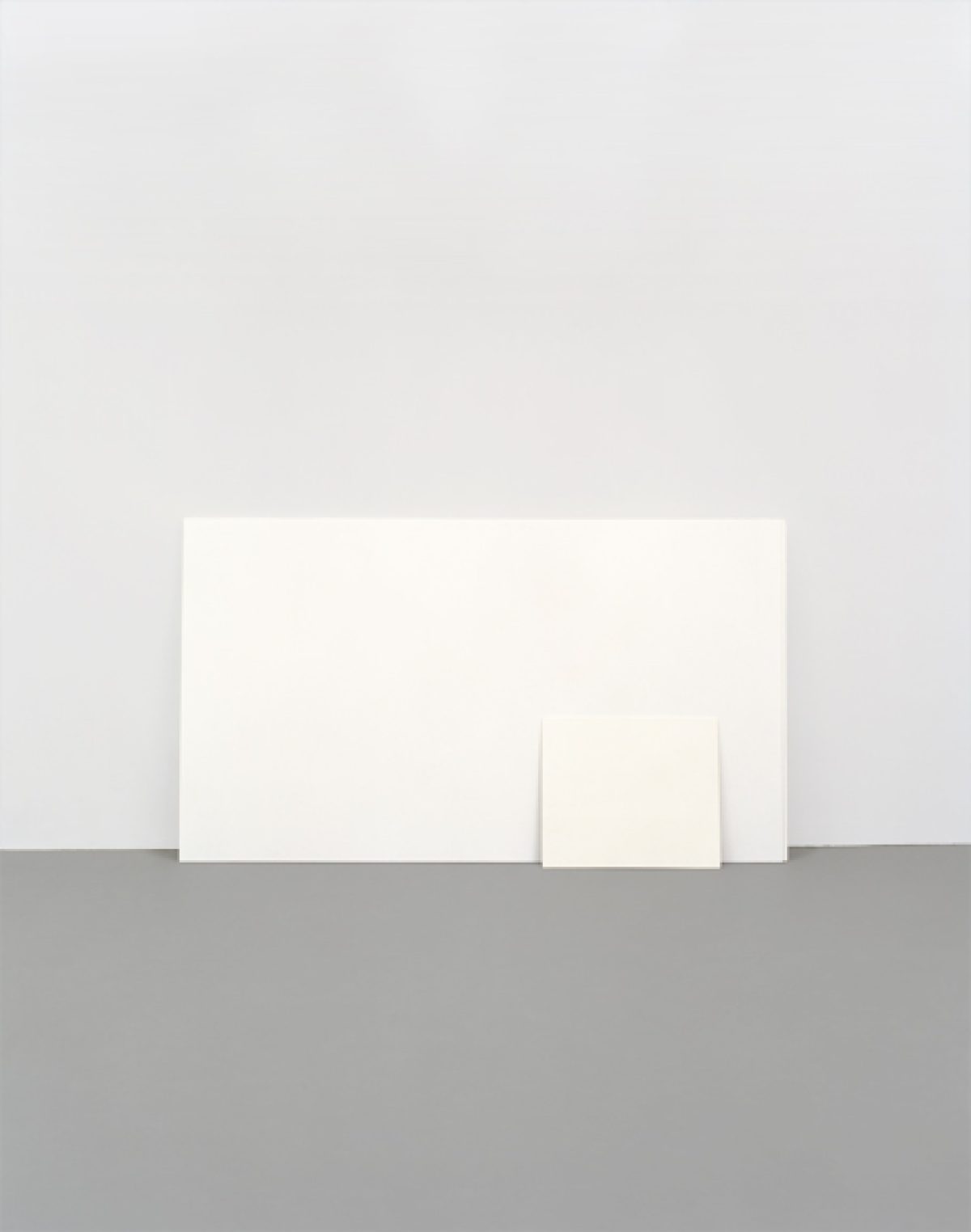 Minimalist composition featuring white rectangular forms arranged on a gray surface against a pale background, creating a study of geometric shapes, subtle shadows, and tonal variation.