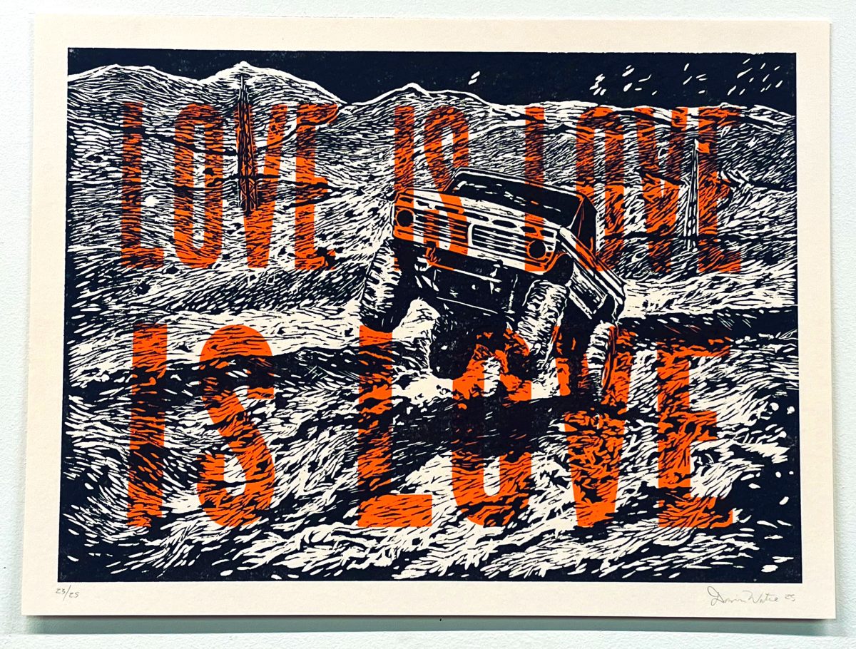 A woodcut print in black, white, orange, and brown depicts a rugged vehicle navigating a desert landscape marked by bold striped patterns. The composition features layered mountains in the background and expressive linear hatching throughout, creating dynamic movement across the composition.