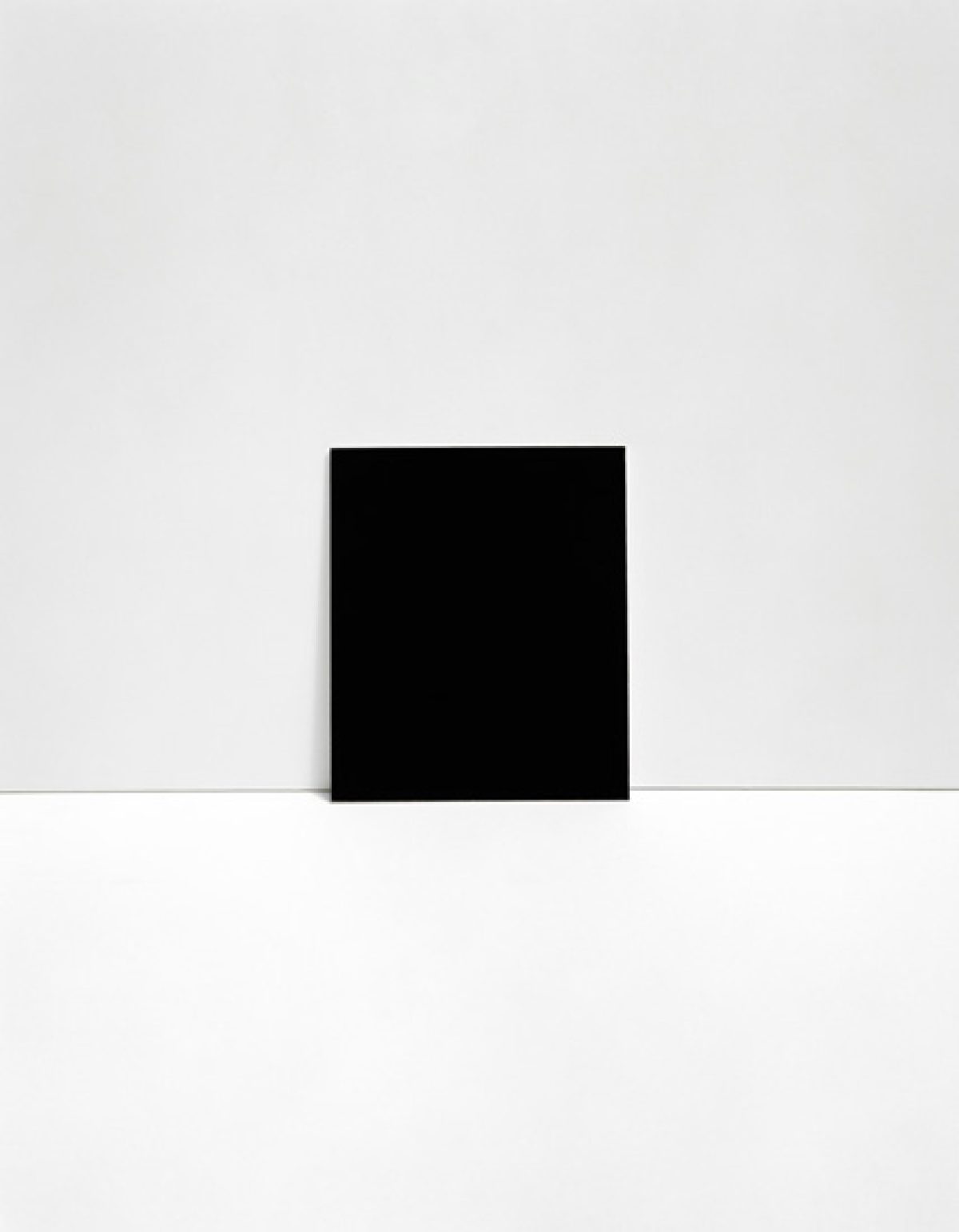 A black rectangular form positioned centrally against a light gray background, bisected horizontally by a darker gray line that suggests spatial division or a horizon line. The composition emphasizes minimalist geometry and tonal relationships.