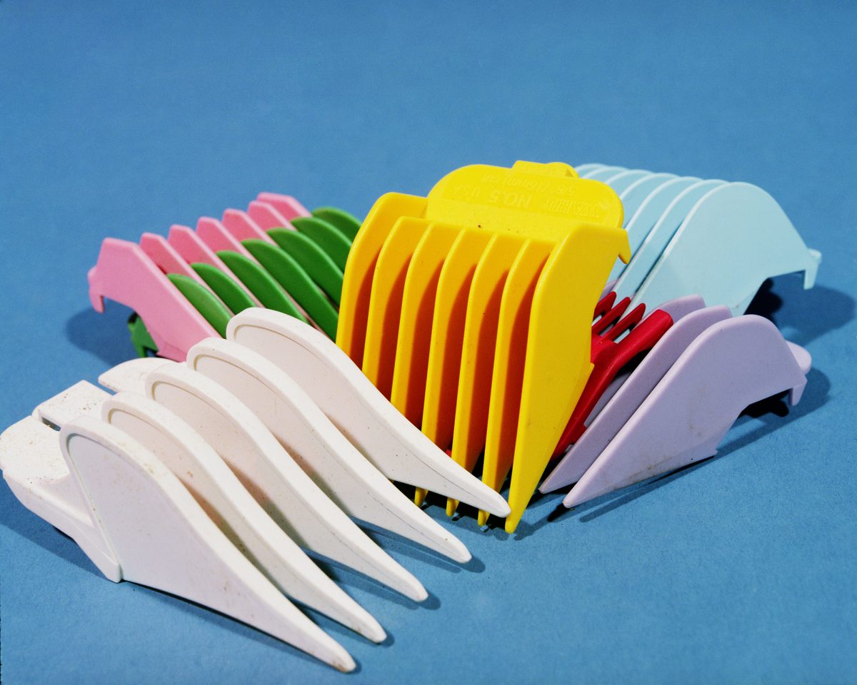 Colorful plastic hair clips arranged in overlapping rows against a bright blue background, displaying shades of white, pink, green, yellow, red, light blue, and purple in a playful still-life composition.