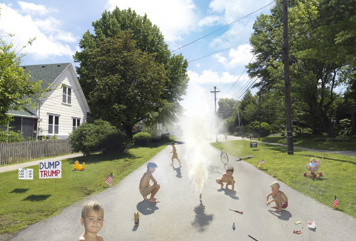 A suburban street scene depicts children playing among smoke and fire, with a white house, utility pole, and manicured lawns flanking the road. Political signage reading "DUMP TRUMP" appears on the left yard, while American flags are scattered throughout the composition, creating a surreal juxtaposition of domestic innocence and chaos.