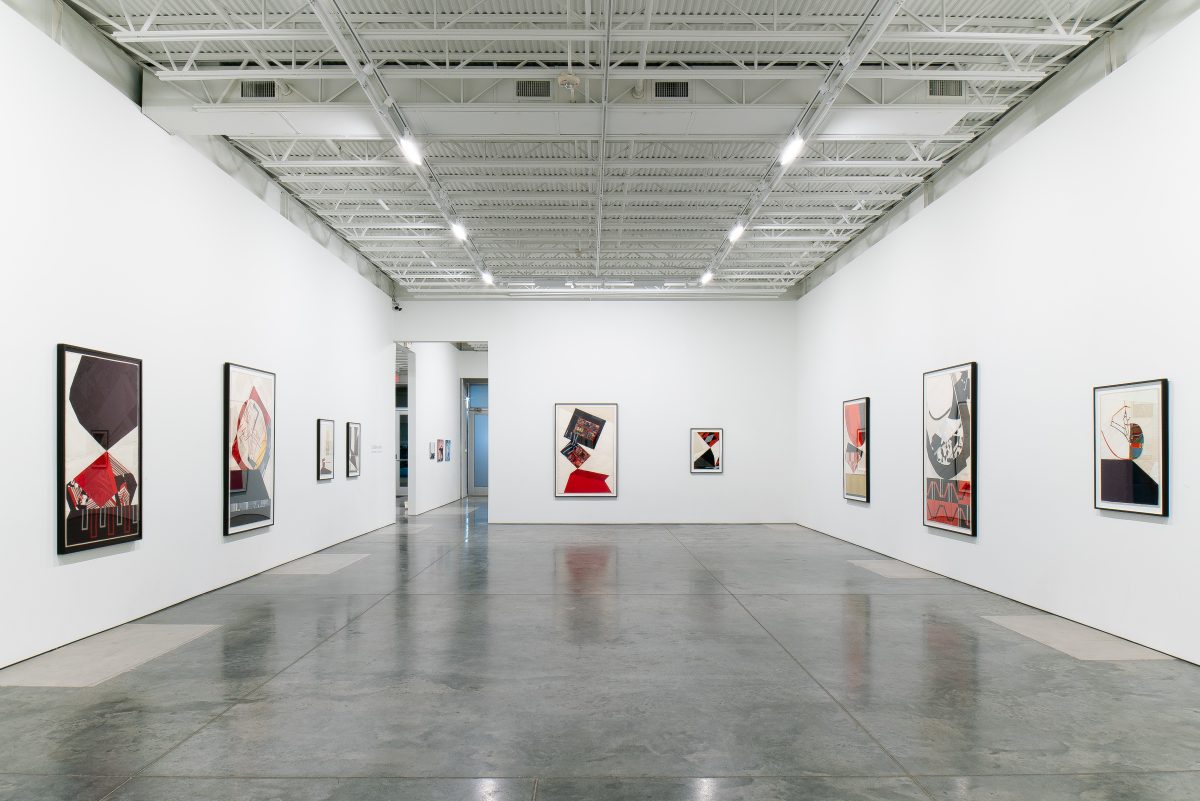 Contemporary textile collages displayed on white gallery walls featuring geometric abstractions in deep reds, blacks, and neutrals created from layered vintage fabrics; polished concrete floor reflects the carefully spaced framed works under industrial ceiling lighting.