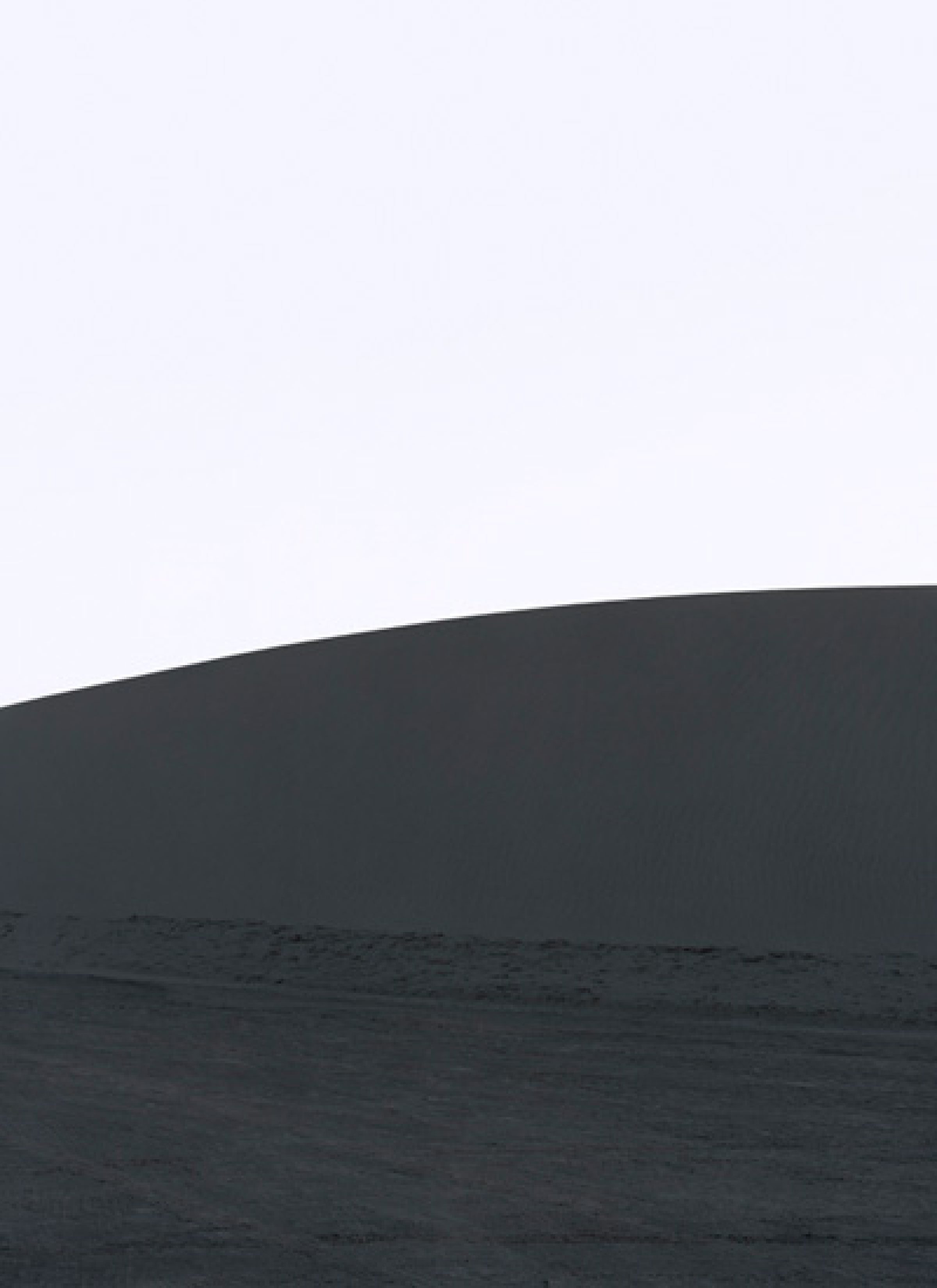 Minimalist composition dividing the frame horizontally into a pale upper section and dark lower half, with a curved horizon line suggesting an abstract landscape or geological formation. Subtle tonal gradations and soft focus create a contemplative, atmospheric quality.