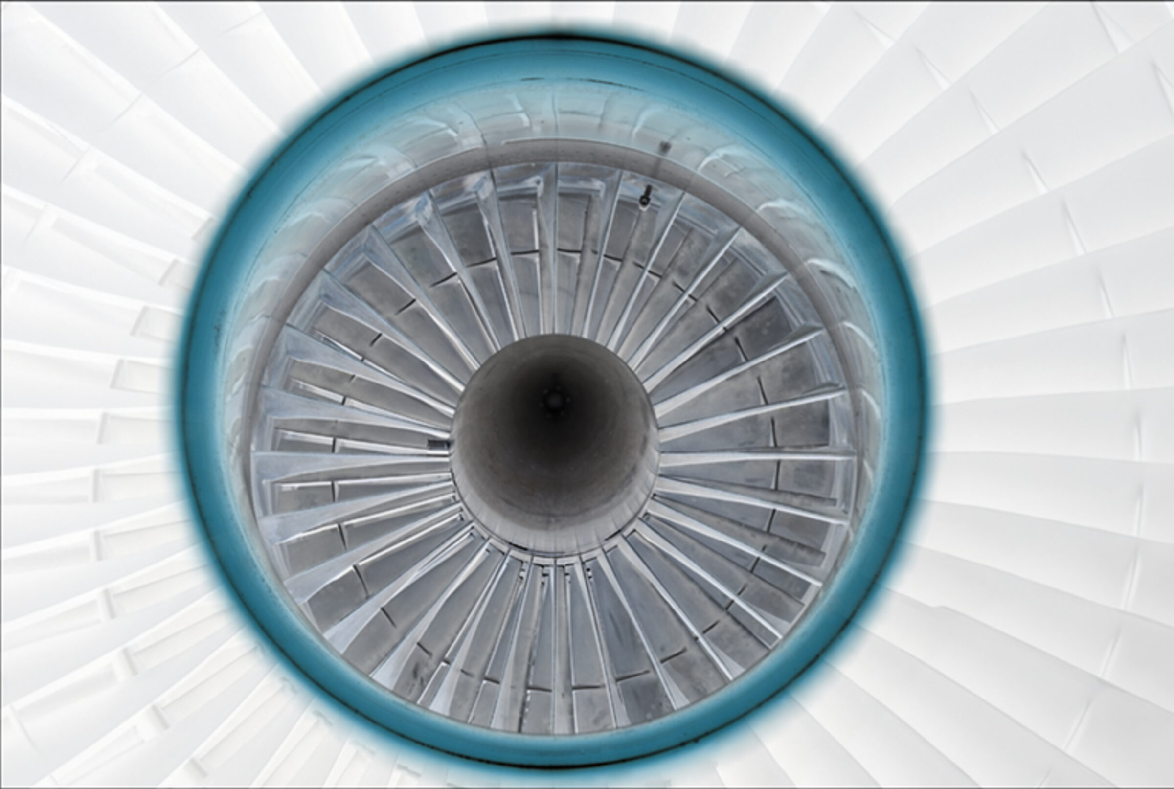 Symmetrical overhead view of a jet engine intake, featuring concentric rings of metal blades radiating from a dark central core, framed by a turquoise outer ring against a pale geometric background.