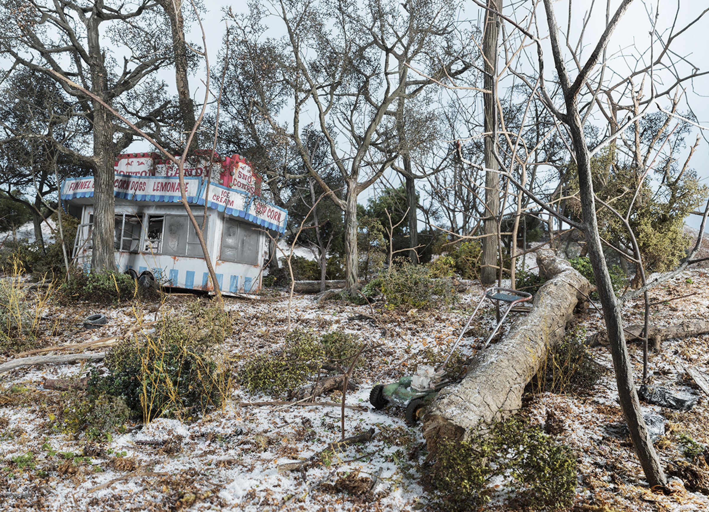 Abandoned concession stand with red and blue striping sits among bare trees and overgrown vegetation in a desolate landscape. The small structure displays faded signage for items like lemonade and ice cream, surrounded by fallen logs, scattered debris, and encroaching nature.