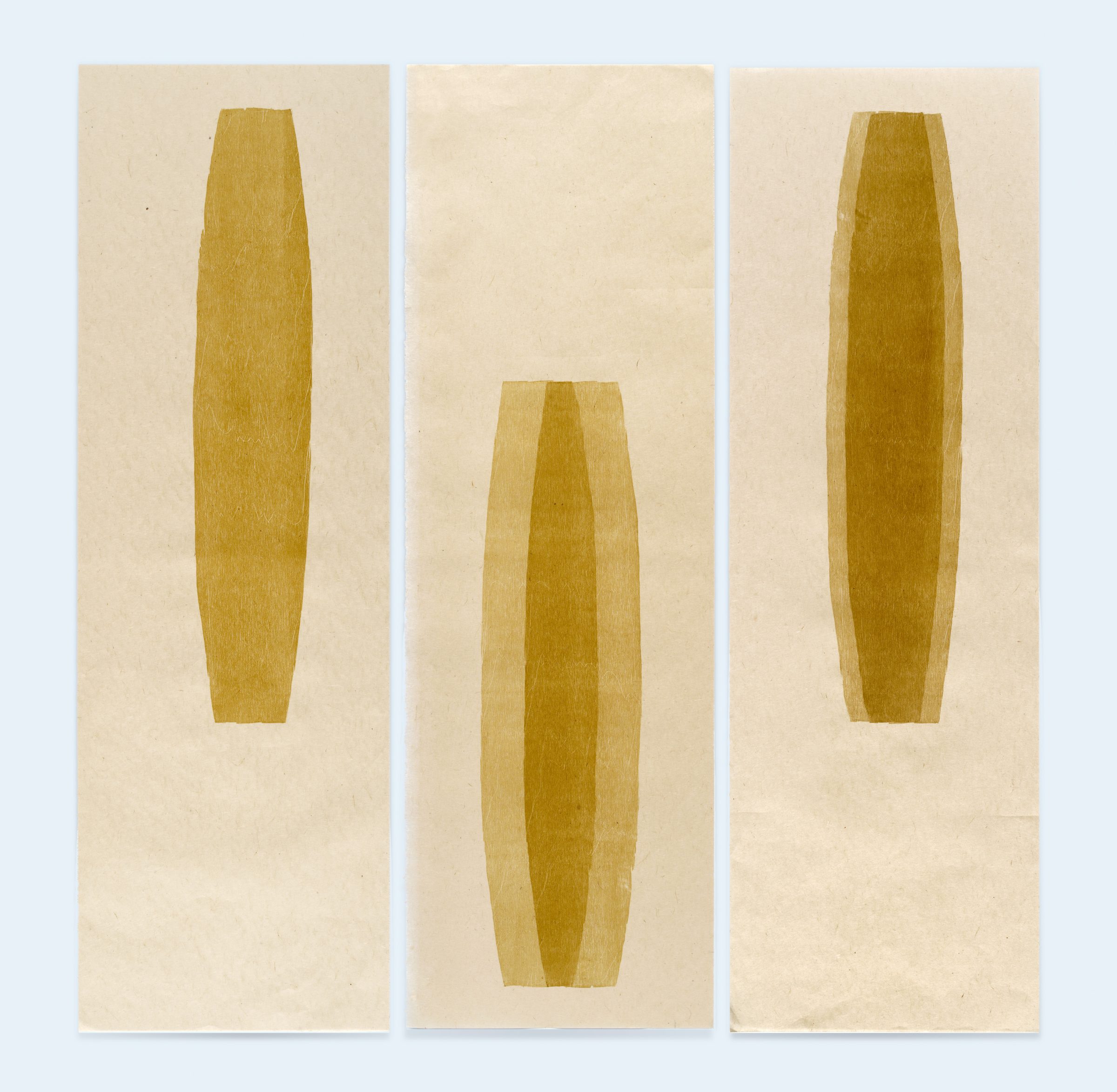 Three vertical panels featuring golden-brown elongated oval shapes on cream-colored paper. The left and right panels display similar narrow forms with subtle shading, while the center panel shows a wider, more tapered oval with deeper tonal variations creating dimensional depth.