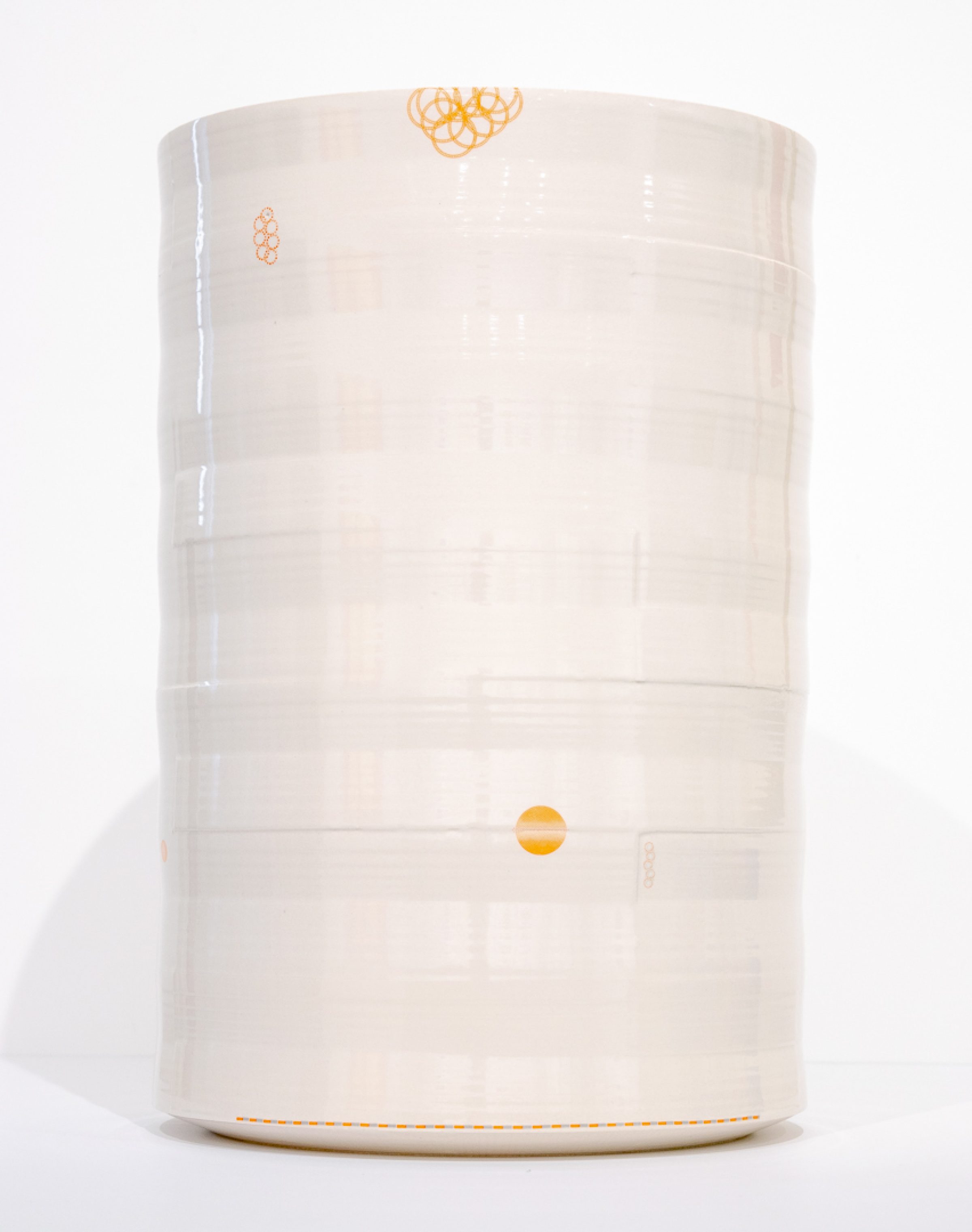 A cream-colored cylindrical porcelain vessel with horizontal ridges and delicate orange line drawings scattered across its surface, including abstract scribbled motifs near the top and a solid circle positioned on the lower section. The vase is photographed against a white background with subtle shadowing.
