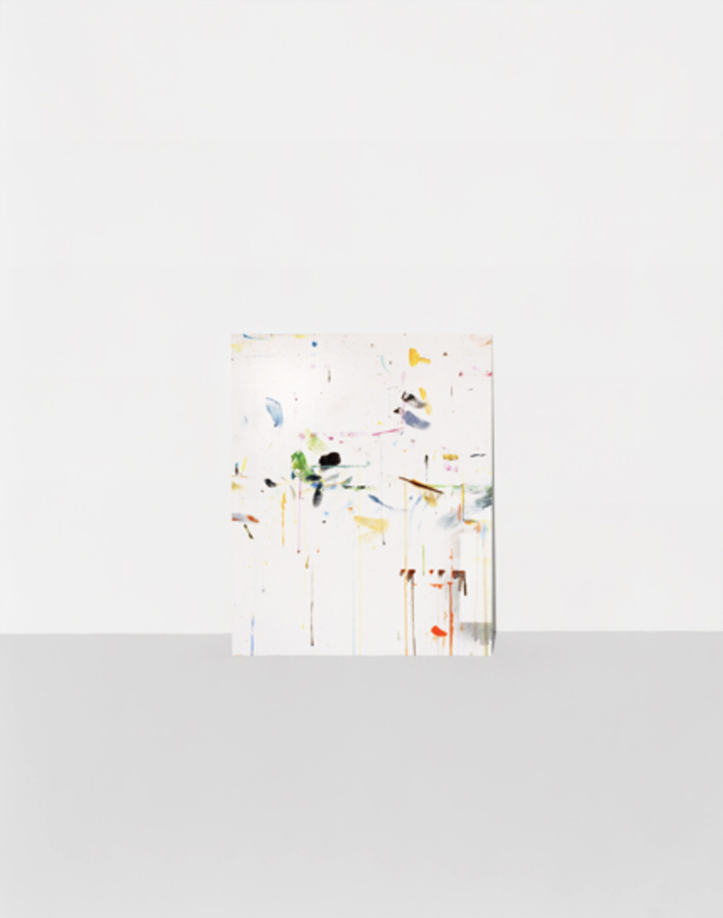 Abstract composition featuring scattered geometric shapes and organic forms in muted yellows, greens, blues, and earth tones arranged across a predominantly white background, creating a sense of dispersed movement and spatial depth.