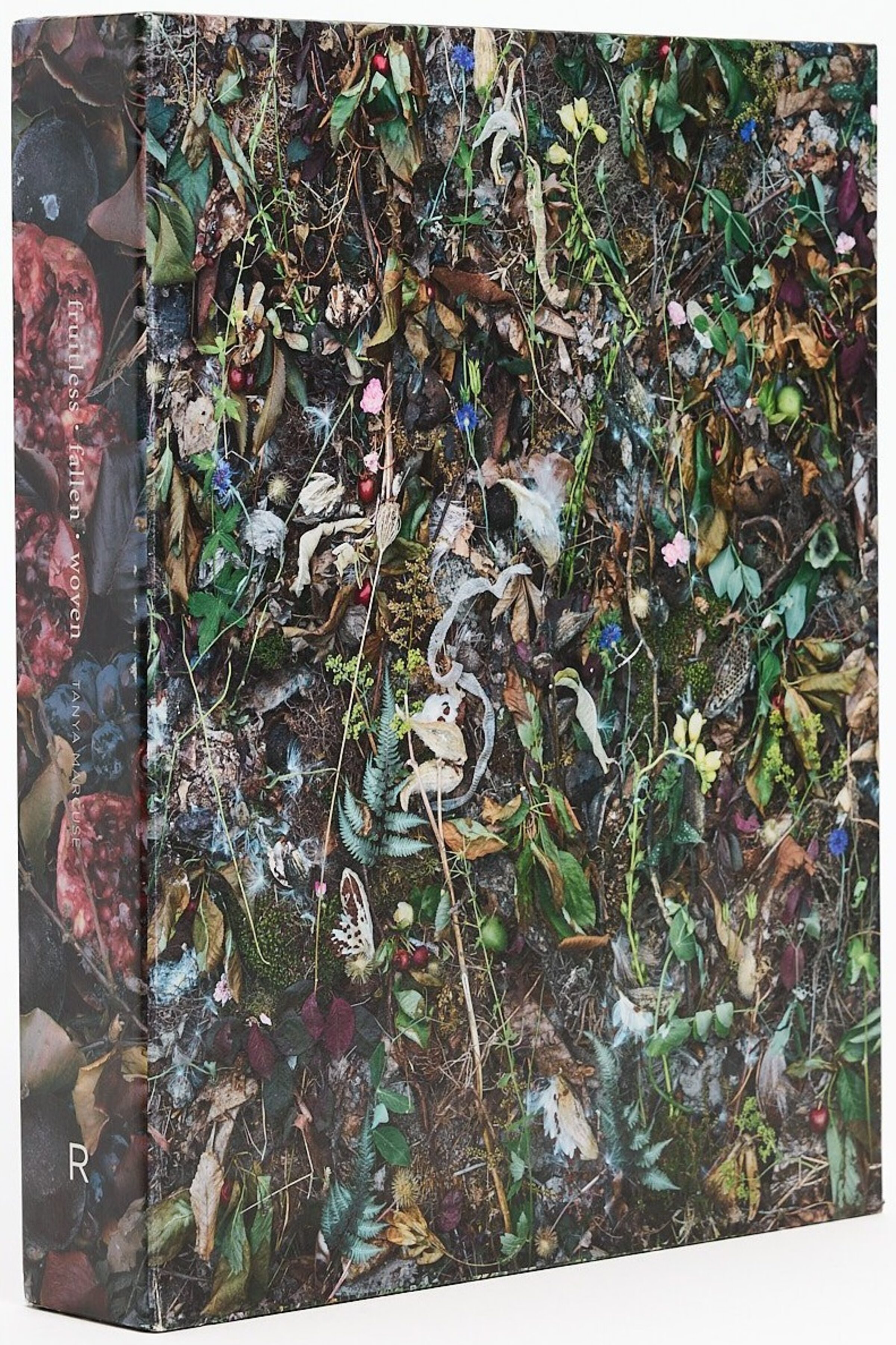 Slipcase for Fruitless | Fallen | Woven by Tanya Marcuse, photographed at an angle, covered in densely arranged plants, fruit, and organic material.