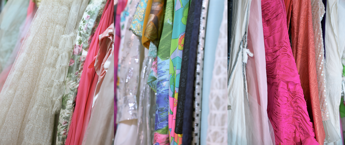 Rows of hanging fabric garments in varying colors and patterns, including floral prints, solid hues of pink, magenta, rust, and cream, with different textures ranging from sheer and delicate to textured weaves, displayed as if on a clothing rack or line.