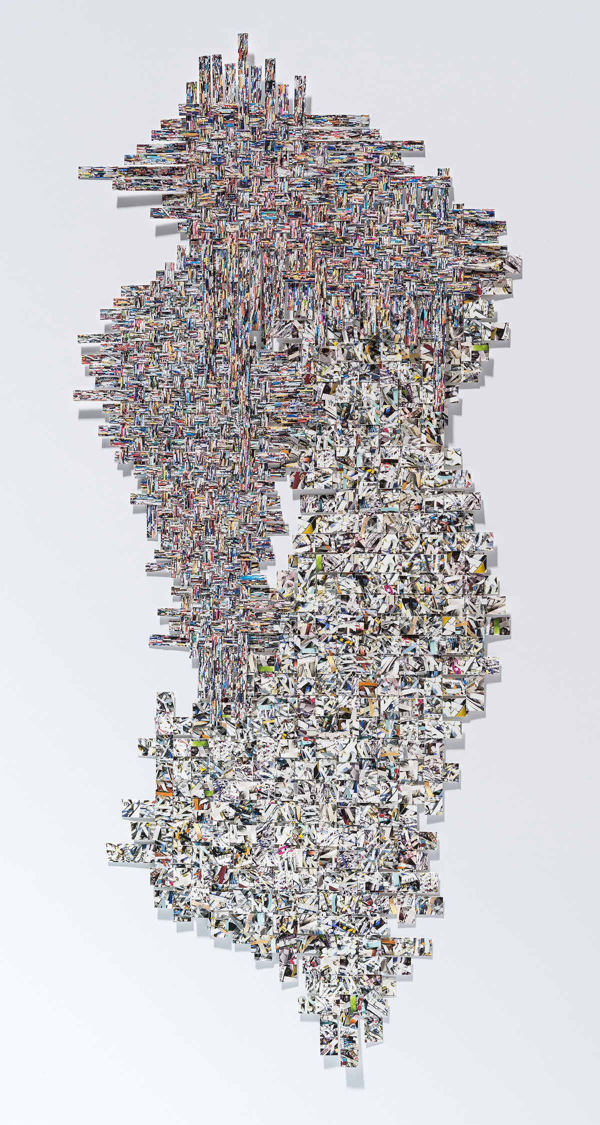 A vertical collage composed of hundreds of small photographic fragments arranged in a dense, organic pattern. The upper portion features tightly layered colorful images creating an intricate woven texture, while the lower half transitions to predominantly white and grayscale fragments that taper toward the bottom, creating a cascading effect against a white background.