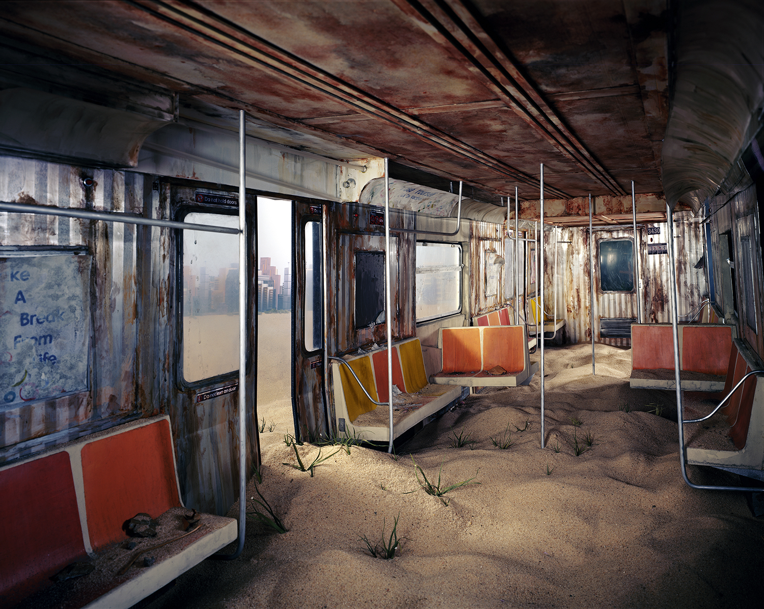 An abandoned subway car interior filled with sand and sparse vegetation, featuring rust-stained metal walls, orange-red seats, and support poles. Sunlight streams through windows revealing an urban skyline beyond, creating a surreal landscape where nature has reclaimed this once-functional public transit space.