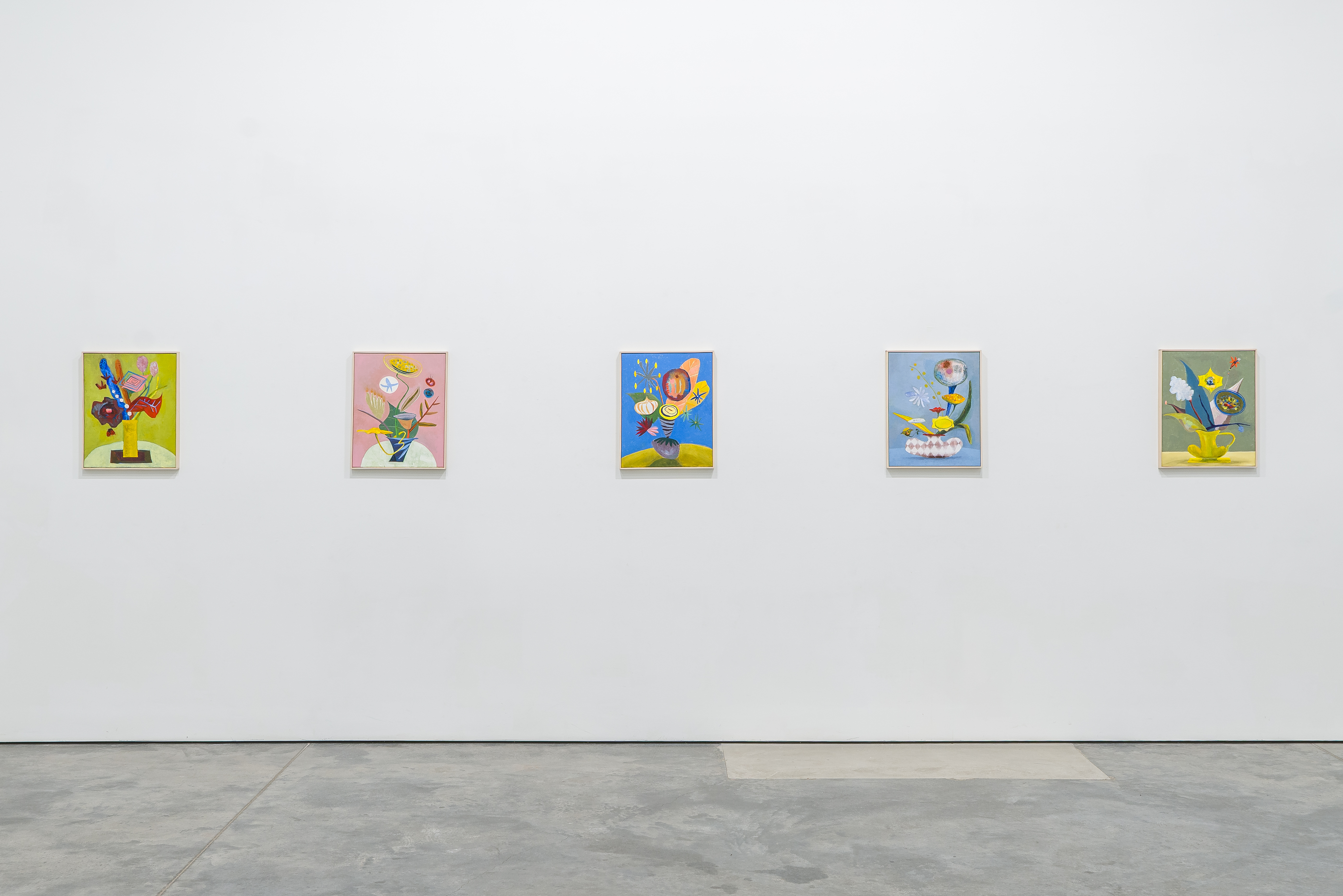 Five vibrant small paintings arranged horizontally on a gallery wall, each depicting stylized floral arrangements in vases against colorful backgrounds. The works feature bold, gestural brushwork and a playful palette of yellows, pinks, blues, and greens, with organic forms suggesting flowers, stems, and vessels rendered in a contemporary expressionist style.
