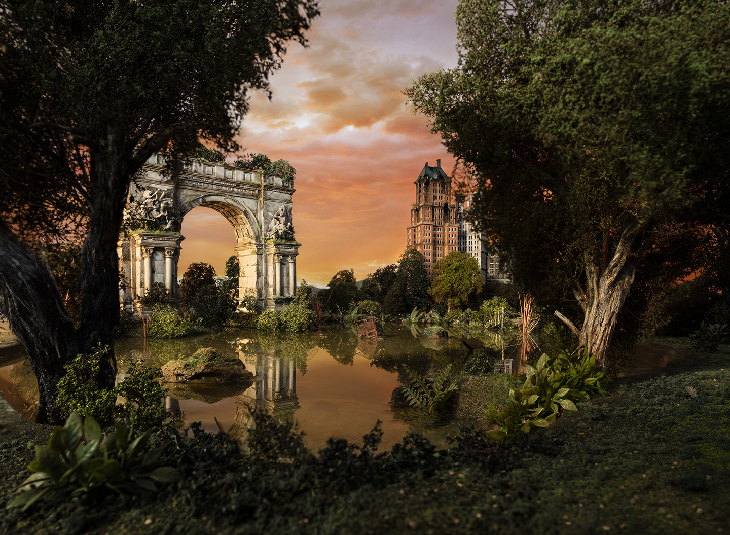 A meticulously composed landscape featuring an ornate classical archway framed by towering trees on either side of a reflective water channel. In the distance, a tall Art Deco building rises against an amber and orange sunset sky, creating a dreamlike tableau that blends architectural grandeur with lush vegetation and atmospheric light.