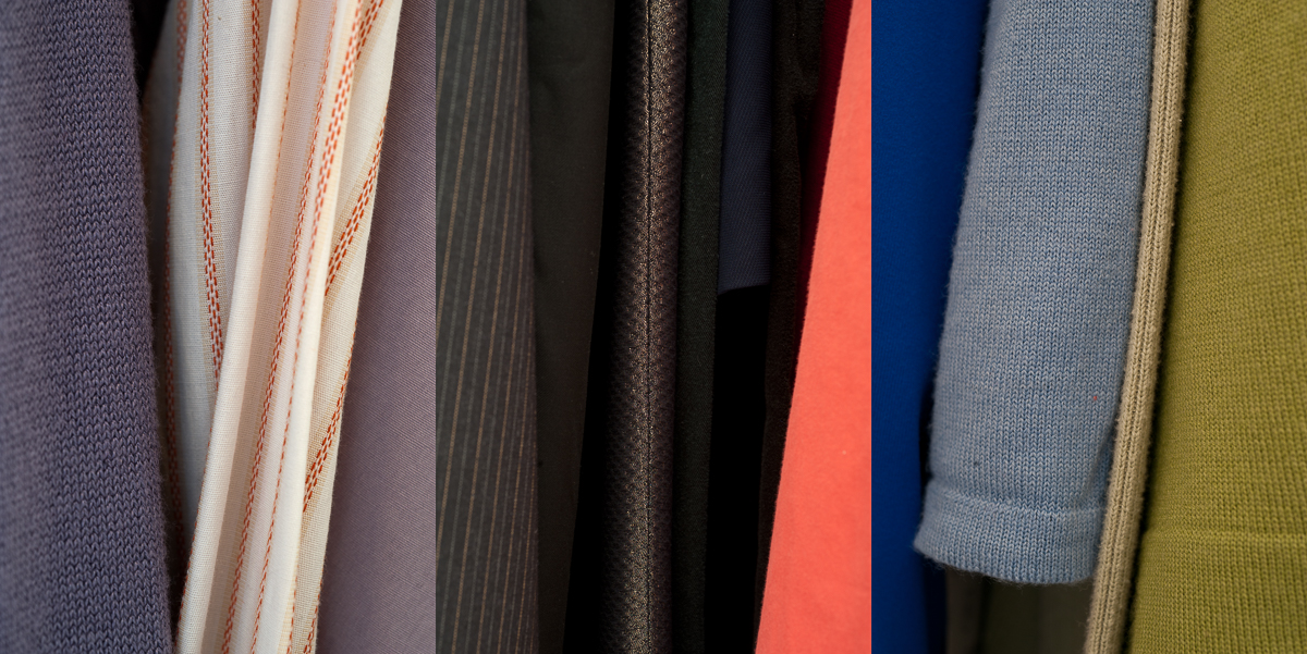 A vertical arrangement of overlapping fabric swatches in varied textures and colors, including muted tones of lavender, cream, charcoal gray, brown, coral, royal blue, pale blue, and olive green, with visible stitching and folded edges creating depth and dimension.