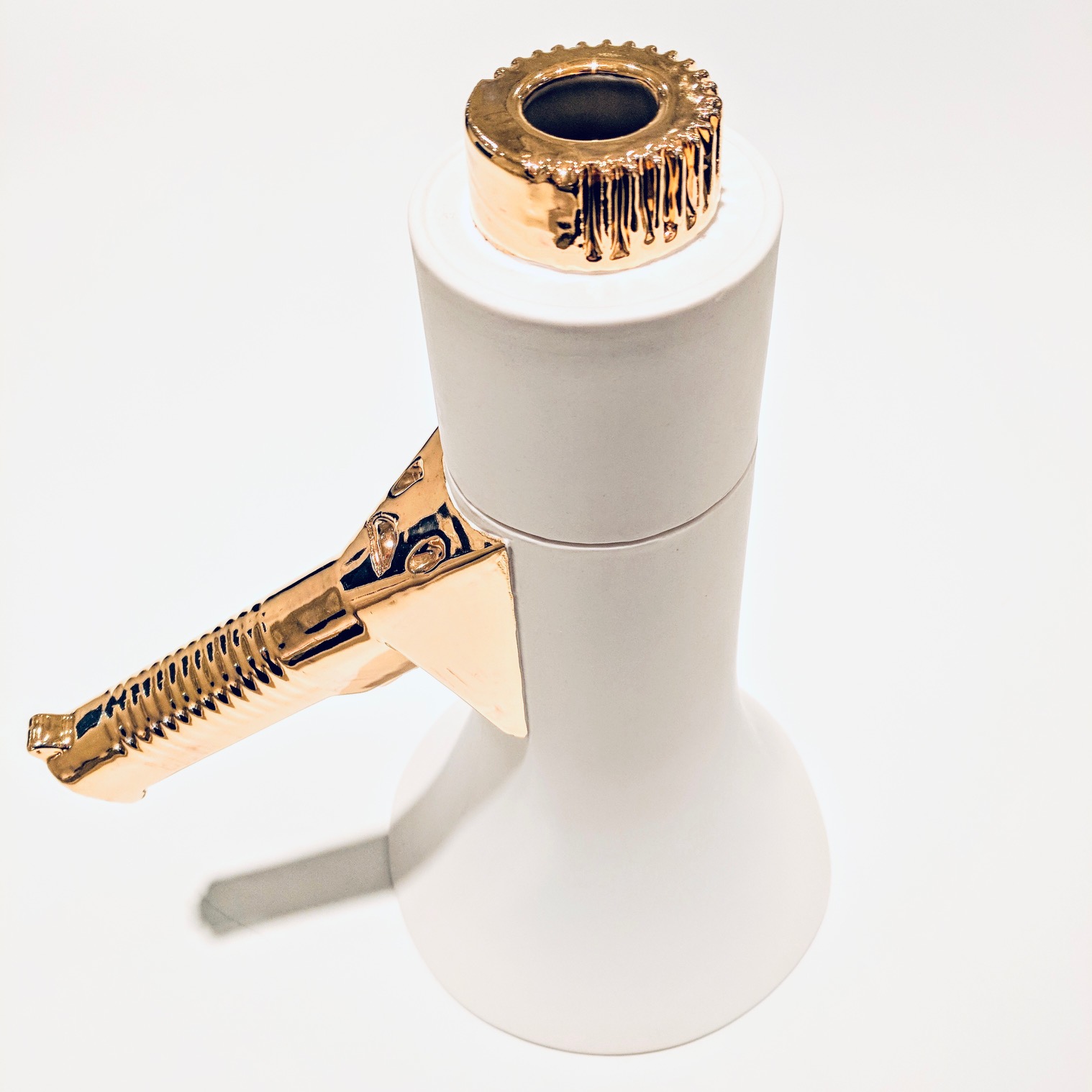 A white porcelain megaphone with a gold-glazed mouthpiece and rim, featuring a decorative handle with dark blue detailing, displayed against a neutral background.