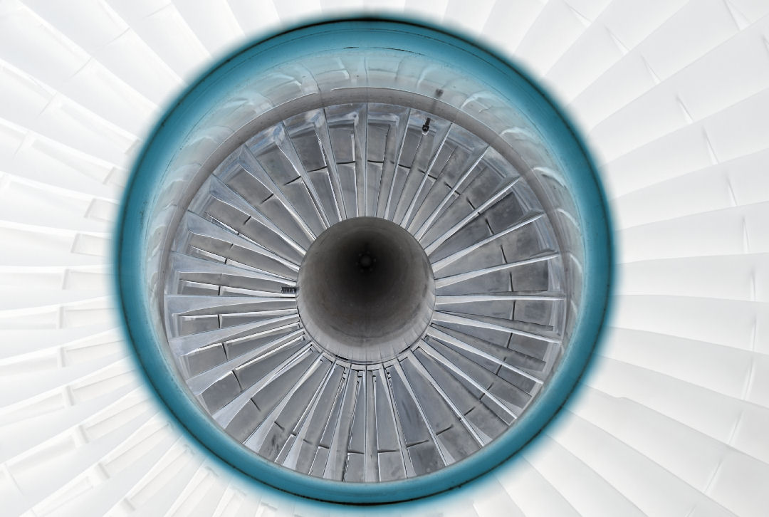 Symmetrical overhead view of a jet engine's interior, featuring concentric circles of gray turbine blades radiating from a dark central core, encased in a bright blue outer ring against a white background.
