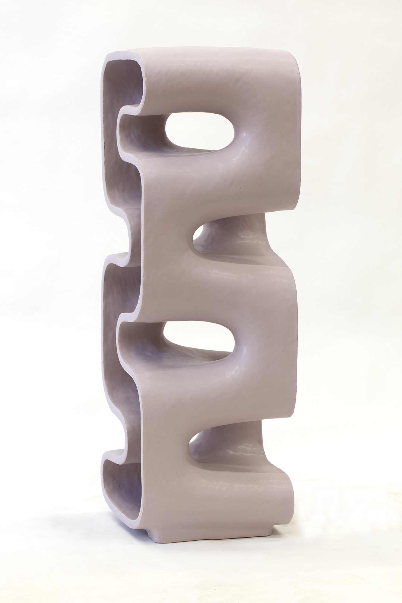 Stacked ceramic form with a pale mauve finish, featuring two squared-off sections connected by curved cylindrical elements. Each section is punctuated by oval cutouts that create negative spaces, revealing the hollow interior and casting subtle shadows across the glazed surface.