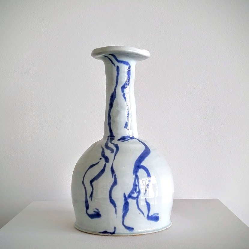 White porcelain bottle with a flared rim and bulbous body, decorated with gestural cobalt blue brushstrokes depicting an abstracted human figure on the front and back. The minimalist linear drawing contrasts sharply against the glossy white surface.